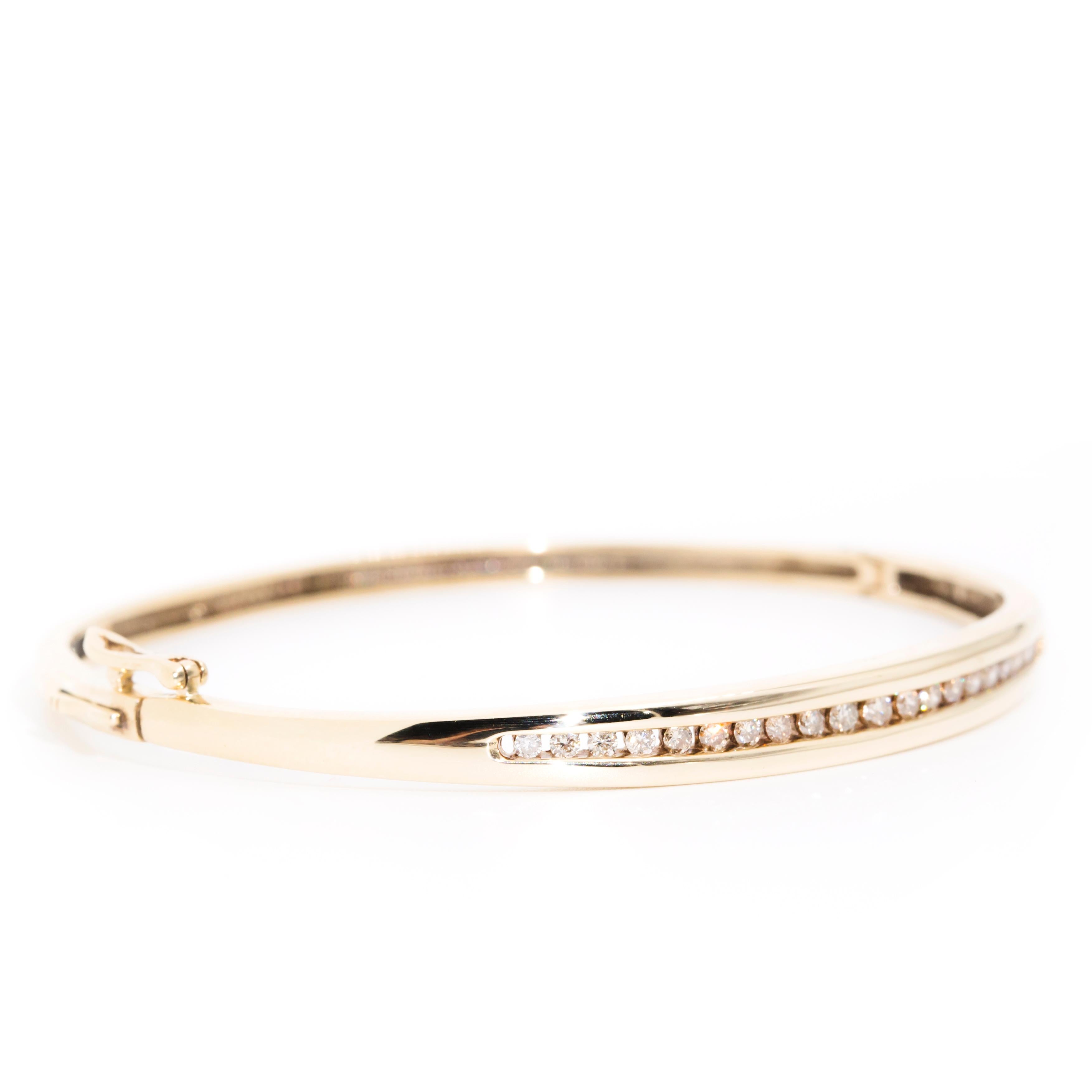 Thoughtfully crafted in 9 carat yellow gold, this elegant vintage adornment is an oval hinged bangle inlaid with a glittering row of twenty round brilliant cut diamonds. This darling vintage piece has been named The Sadie Bangle. She fits