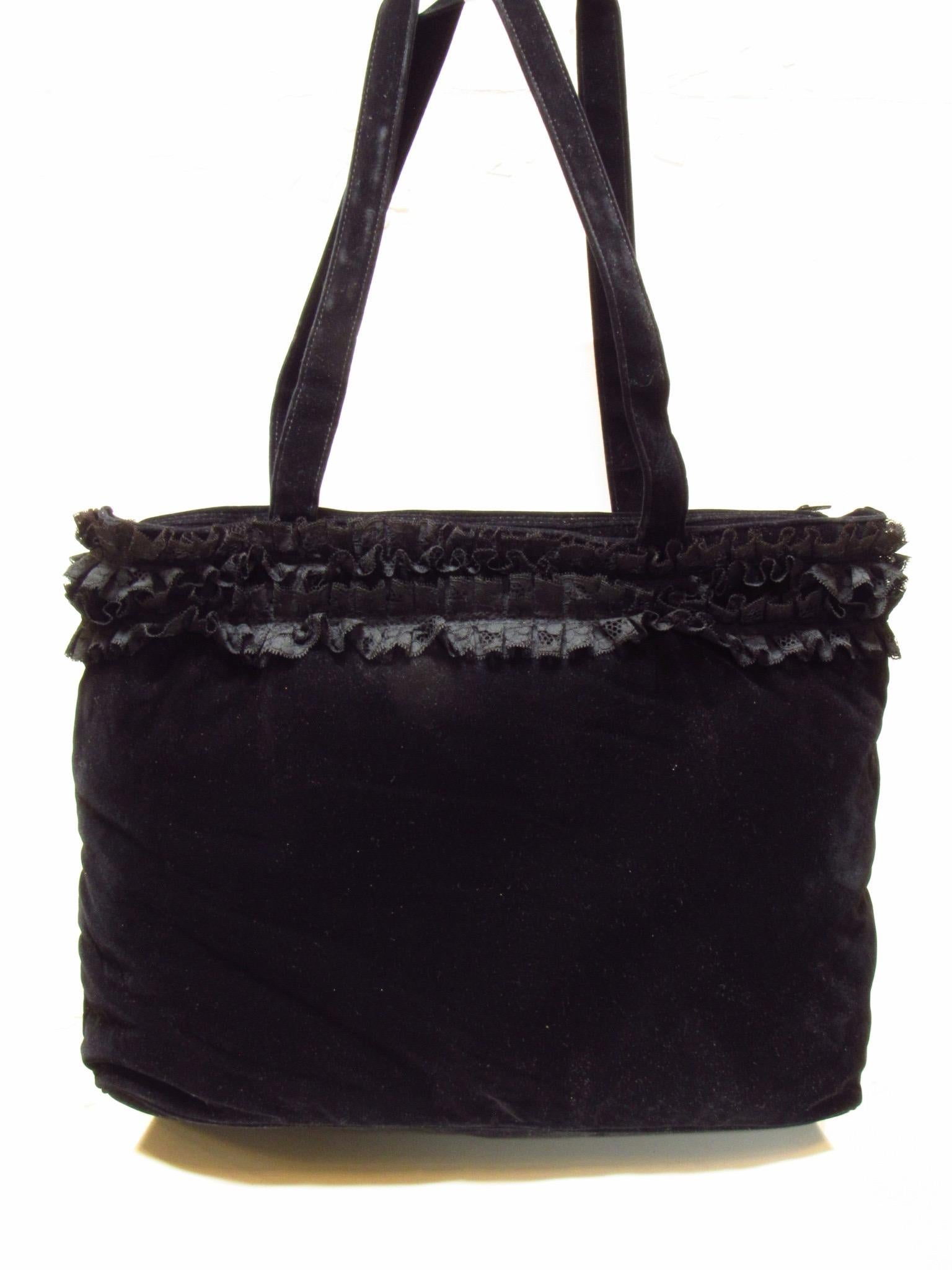 Chantal Thomass black velvet handbag is embellished with lace ruffles around the top. The inside is quilted and offers a zippered pocket. 