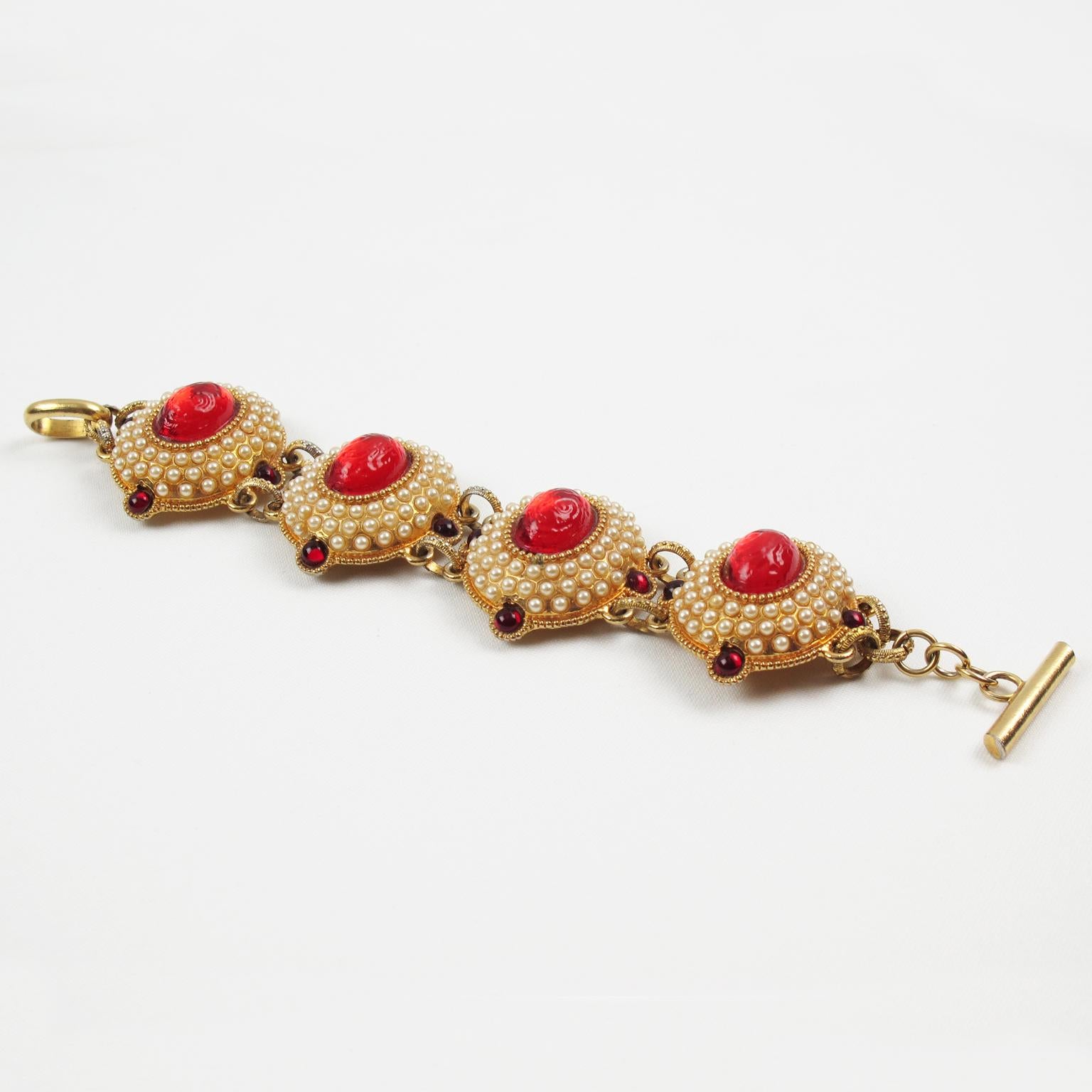 This lovely French Designer Chantal Thomass Paris jeweled link bracelet features gilded-metal carved and domed elements, all paved and ornate with half pearl-like and ruby red cabochons. An impressive ruby-red textured resin cabochon embellishes