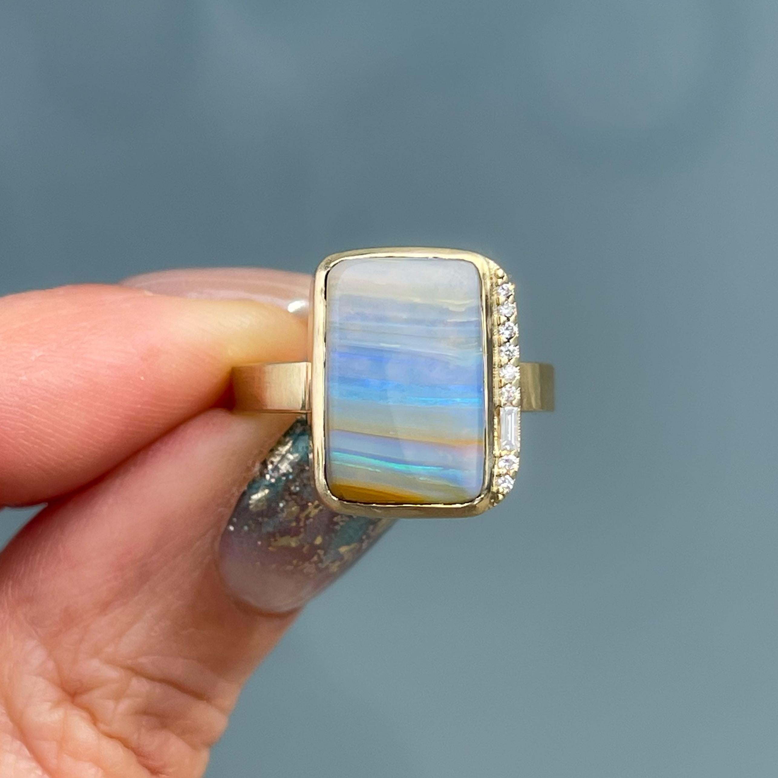 A veil of blue and diaphanous white breezes across this Australian Opal Ring. Palpable within the Boulder Opal is a warm spring day — wispy clouds laced against a cerulean backdrop of dreams. Below, terra firma sets forth a caramel colored pathway —