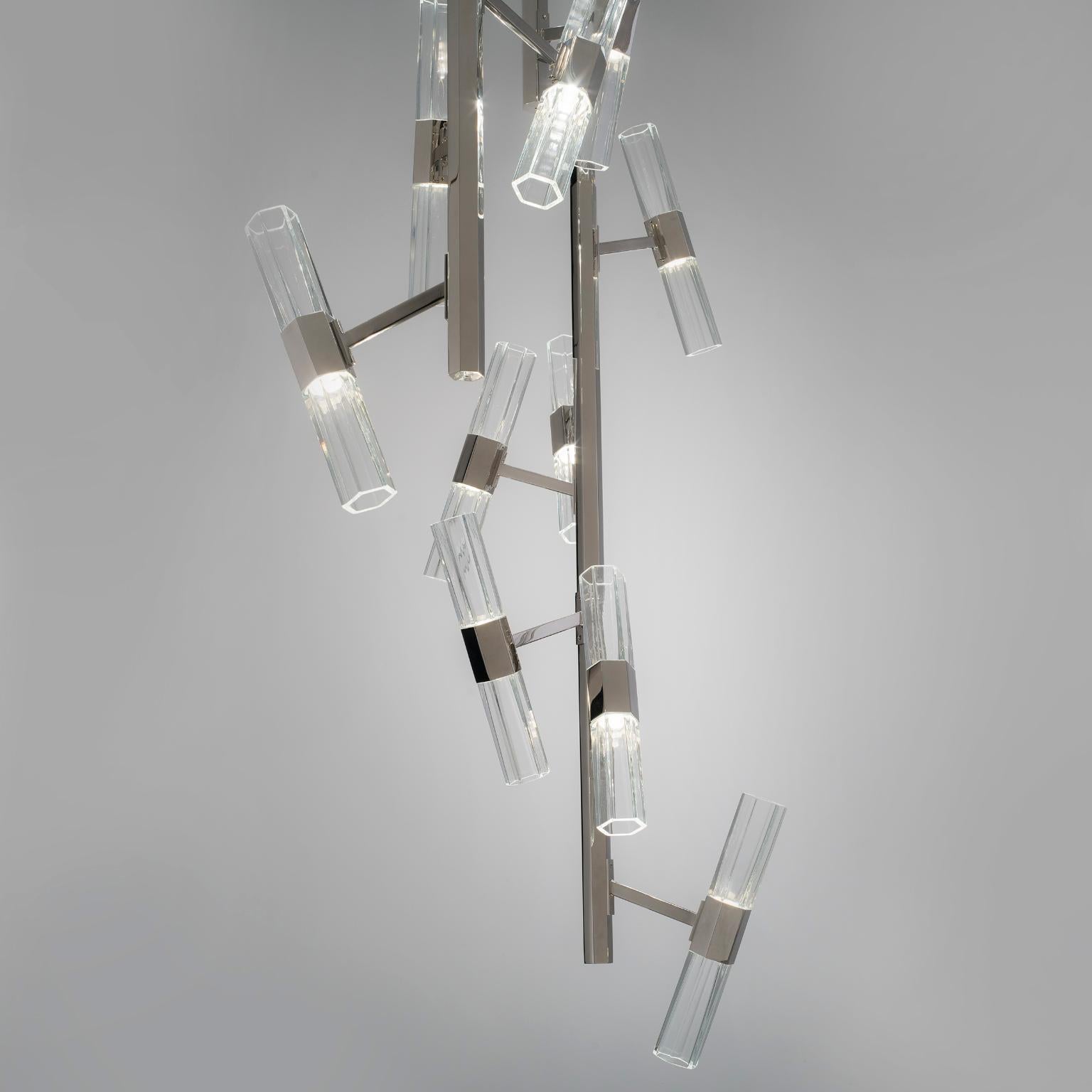 Un caos tranquilo, elegante y sereno. Un sistema estilístico de tonos estructurados donde la verdadera estrella es el módulo hexagonal, disponible en cristal soplado transparente y blanco o en cristales tallados transparentes. El nombre encierra su