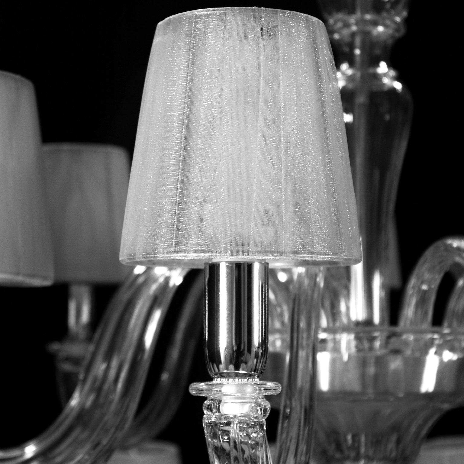 Araña Chapeau 18+9 luces de cristal de Murano, en dos niveles, pantallas de organza plateada hechas a mano por Multiforme.
Chapeau es una lámpara de araña clásica y esencial, fabricada artesanalmente con materiales de alta calidad en cristal de