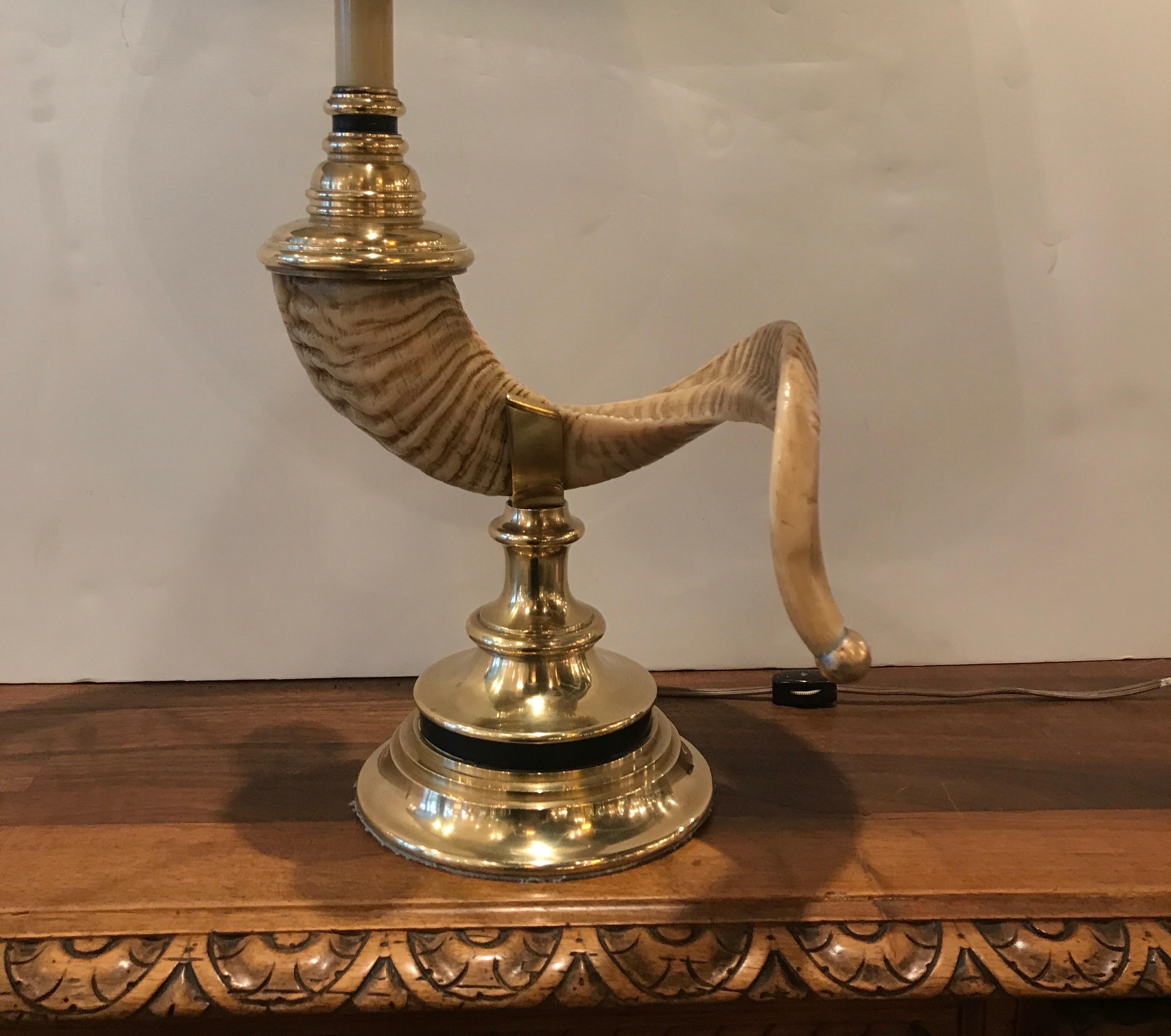 A cast brass chapman lamp in the form of a rams horn. The brass mounts with a resin formed horn with black parchment oval shade.