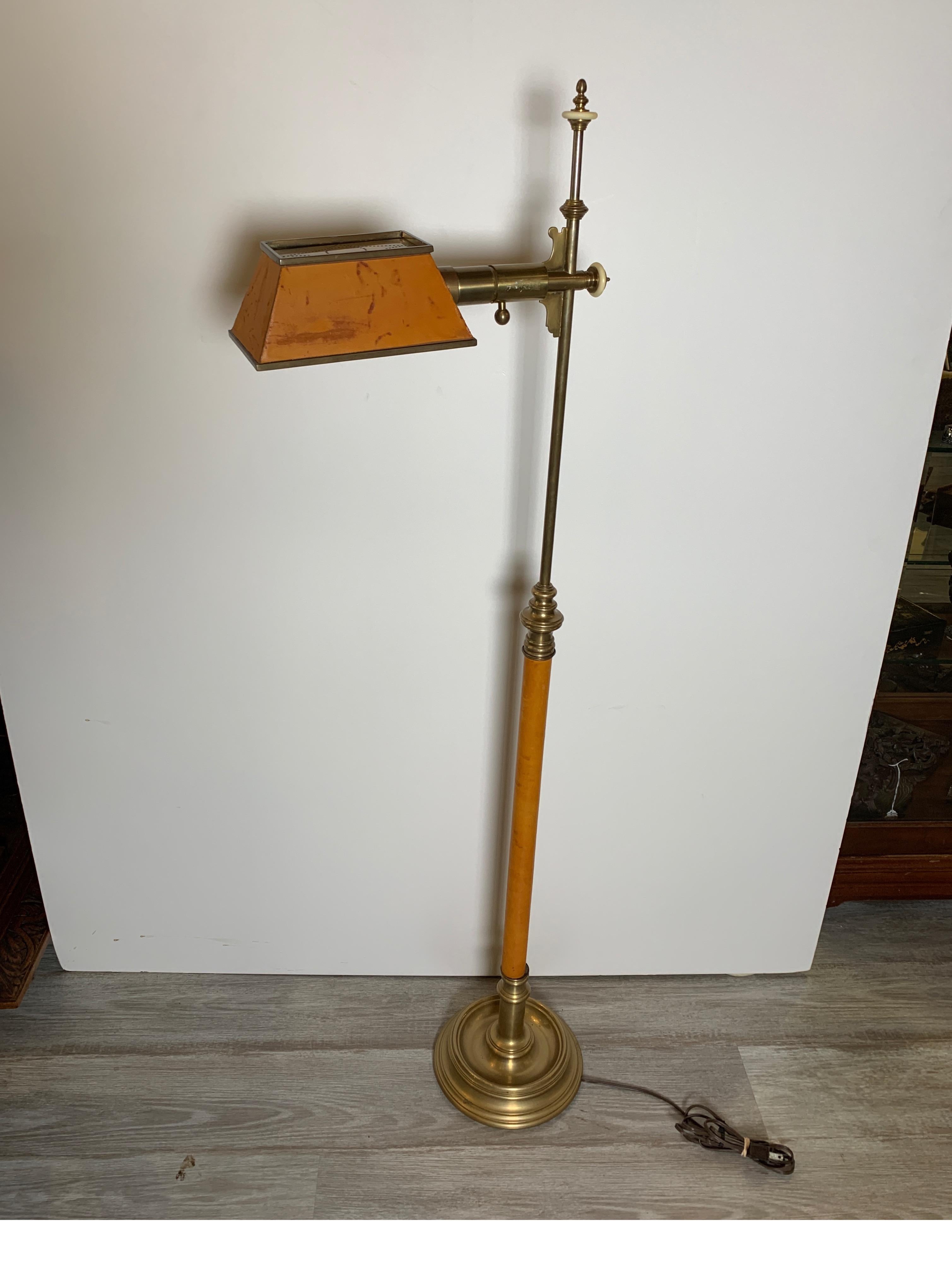 Stylish aged brass floor lamp with leather covered shade and center pole. The cast brass lamp with tapered rectangular shade with top light diffuse supported by a leather wrapped center pole resting on a round molded base. Marked Chapman.