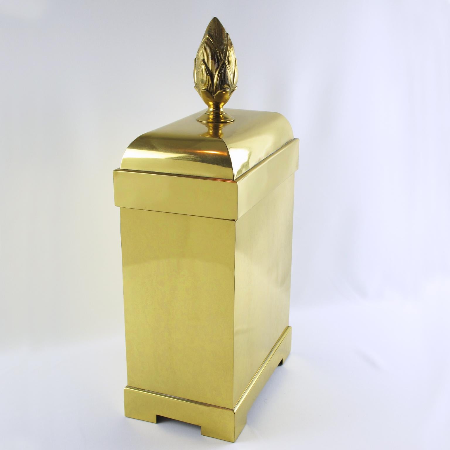Chapman Manufacturing Company designed this stunning oversized lidded brass decorative box or magazine storage stand in the 1980s. The box boasts a tall geometric shape with a massive brass pine cone carved handle. The piece is lined with a black