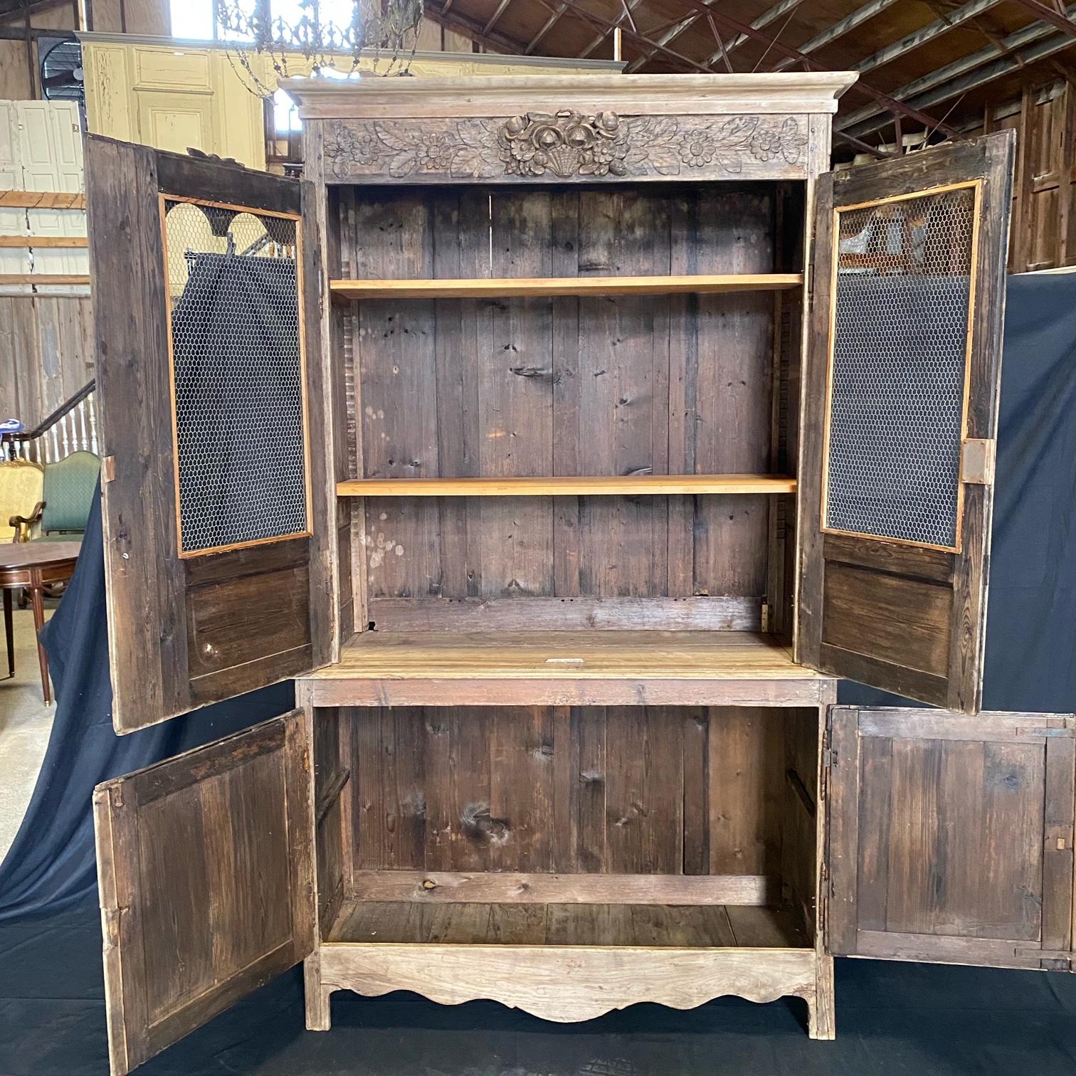 A tall French 19th century carved wood two-piece open mesh cabinet, armoire or bookcase having set back upper case of two doors over a lower case which is comprised of two cabinet doors. Each of the doors feature beautifully carved recessed panels.
