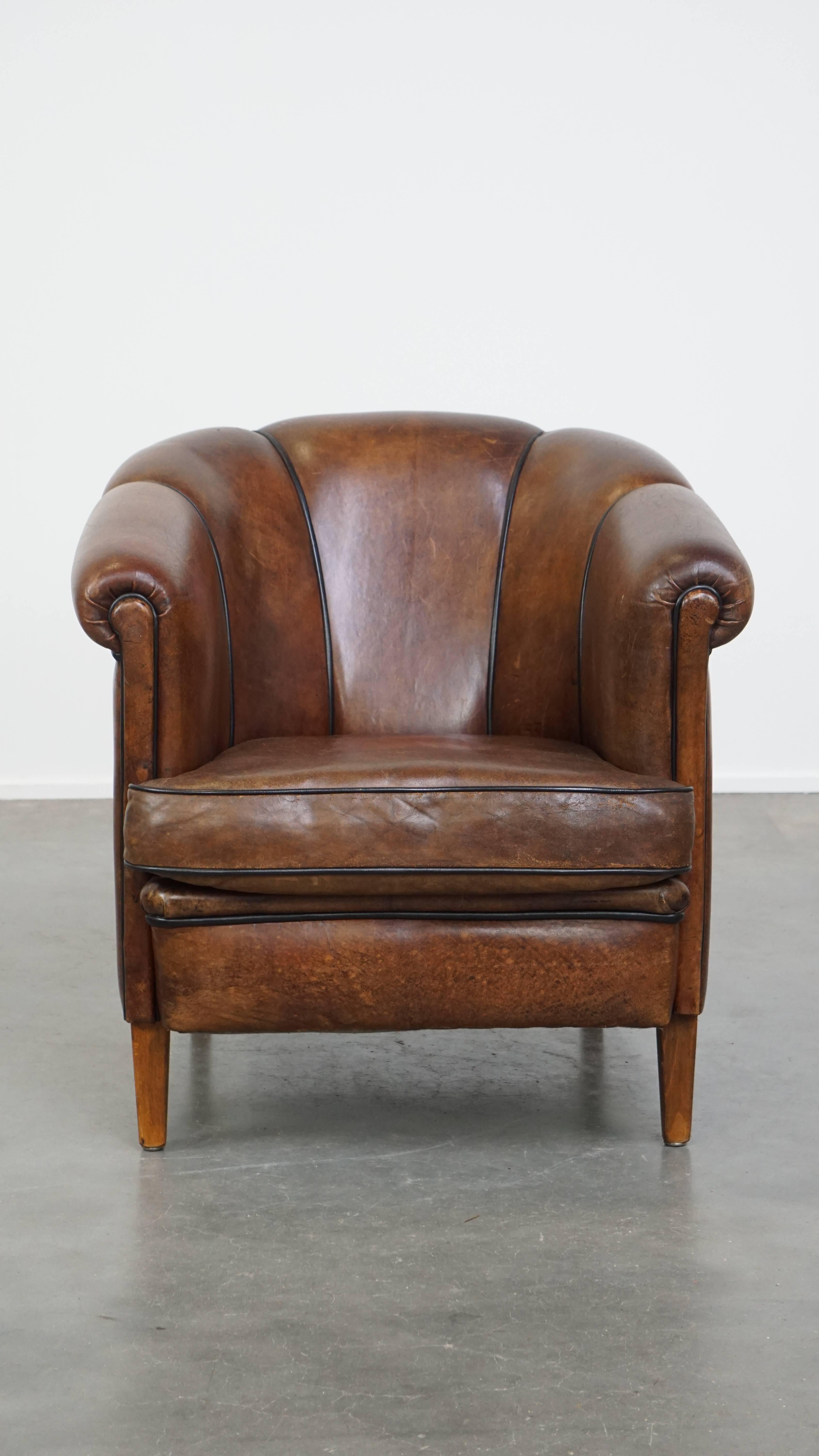Este impresionante sillón club de piel de oveja es un complemento perfecto para quienes aprecian los muebles con un fuerte carácter. Su color oscuro, los distintivos reposabrazos y los refinados detalles de los ribetes negros le dan un aspecto