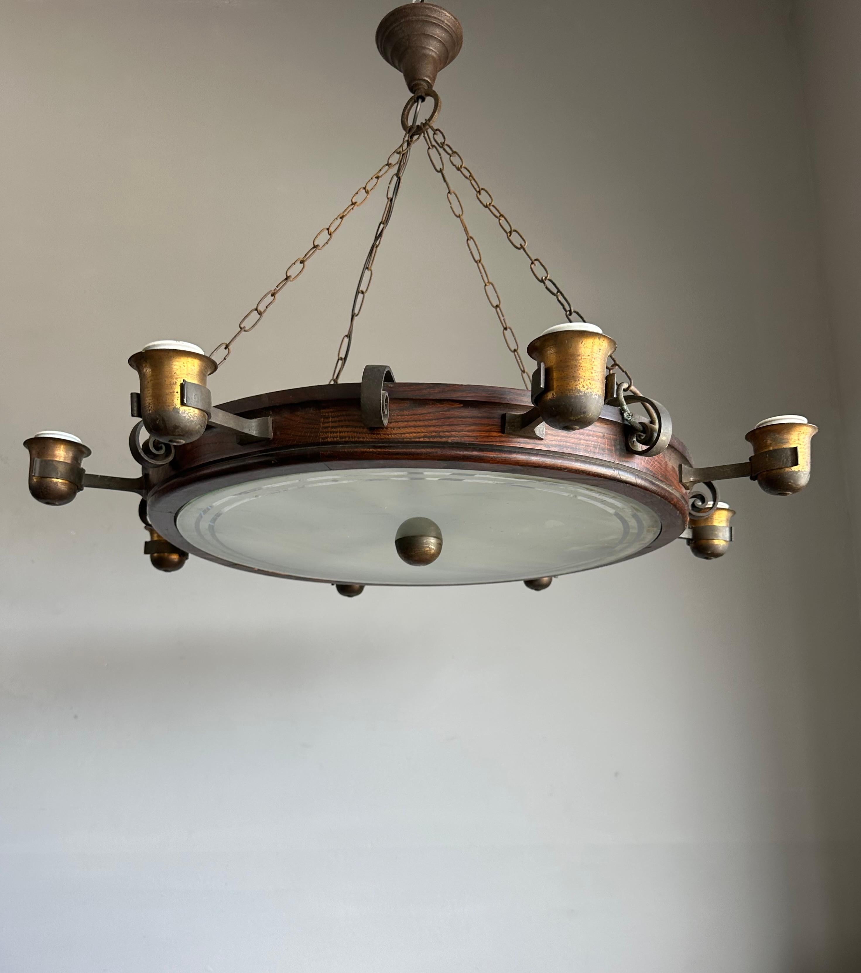 Grand lustre authentique en chêne, fer forgé et laiton - provenant anciennement d'un pub ou d'un restaurant européen.

Cet impressionnant lustre circulaire a probablement été récupéré dans un pub, une brasserie ou un restaurant européen, et il a