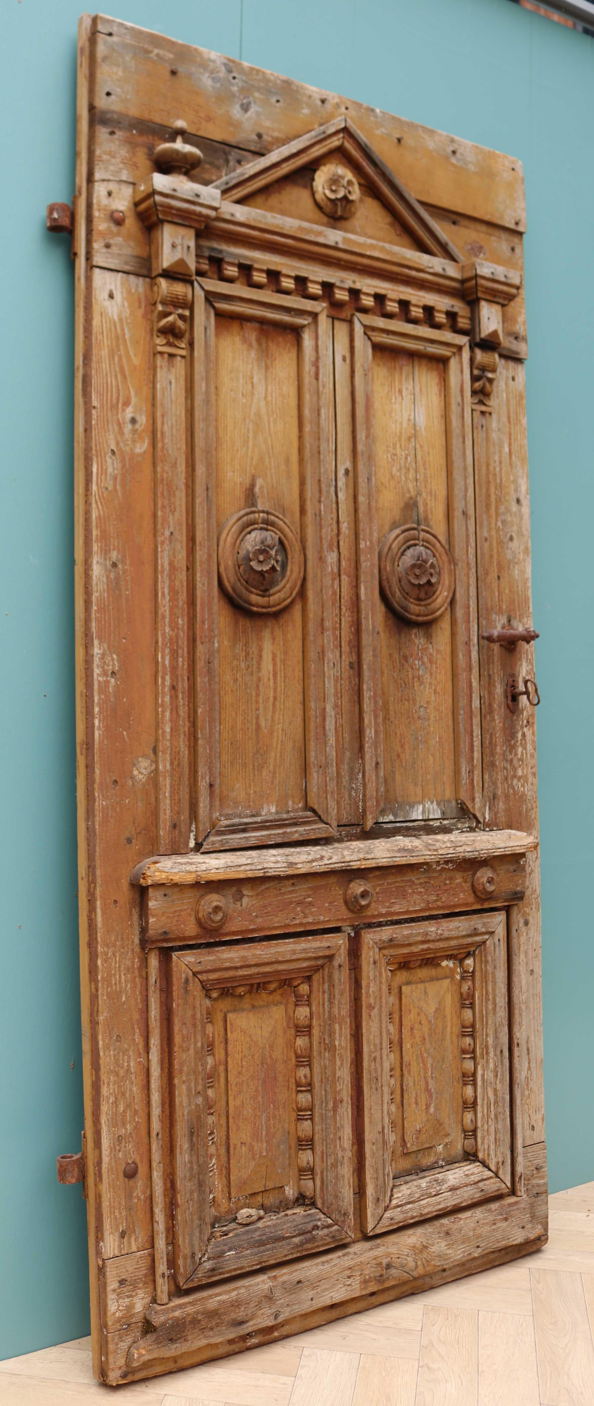 An unusual exterior door constructed from pine, with applied carvings.