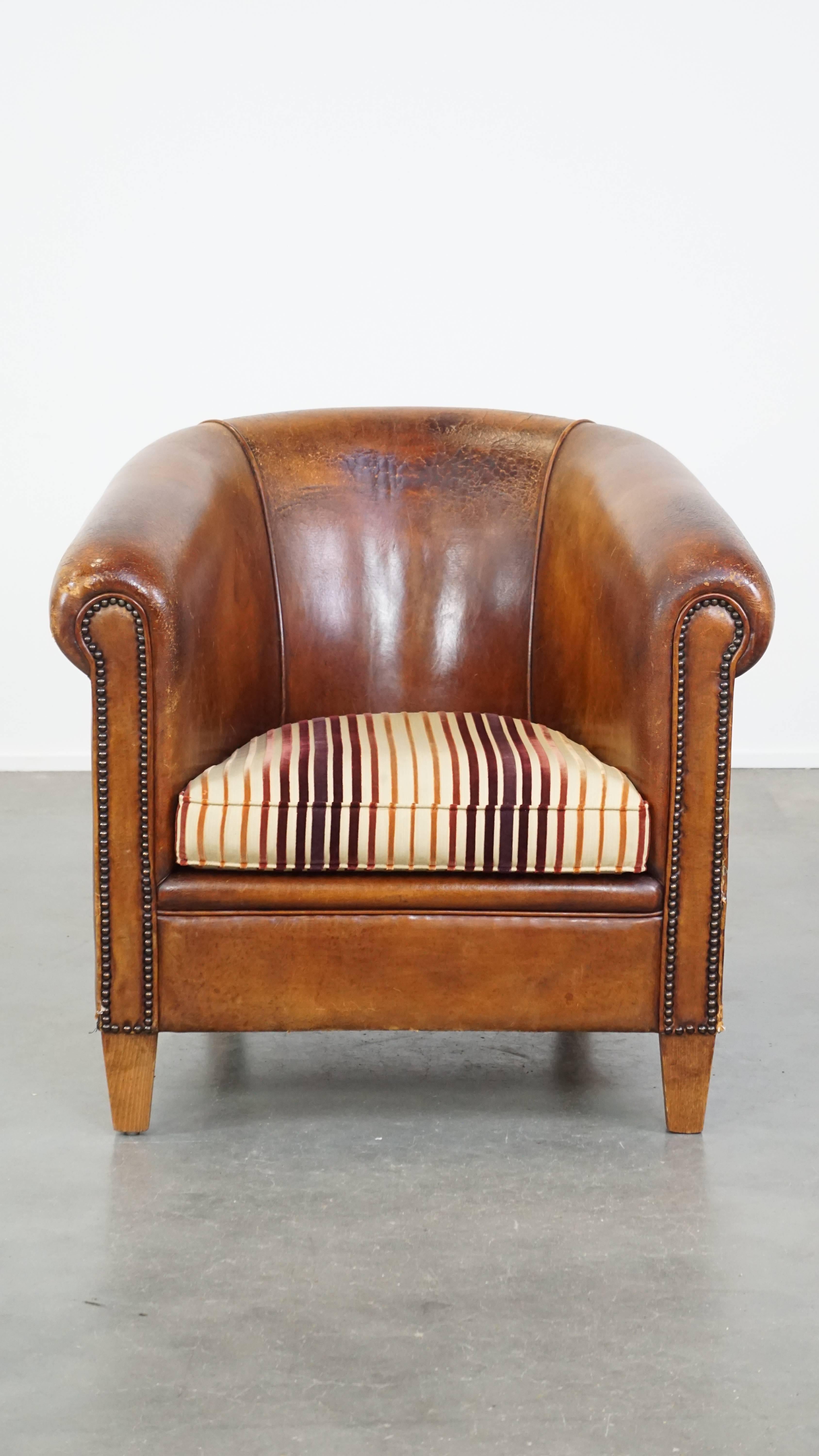 Ce superbe fauteuil club vintage en cuir de mouton est un véritable accroche-regard qui ne devrait manquer dans aucun intérieur. Il présente une belle couleur cognac, est plein de caractère et est élégamment fini avec des clous décoratifs. La chaise