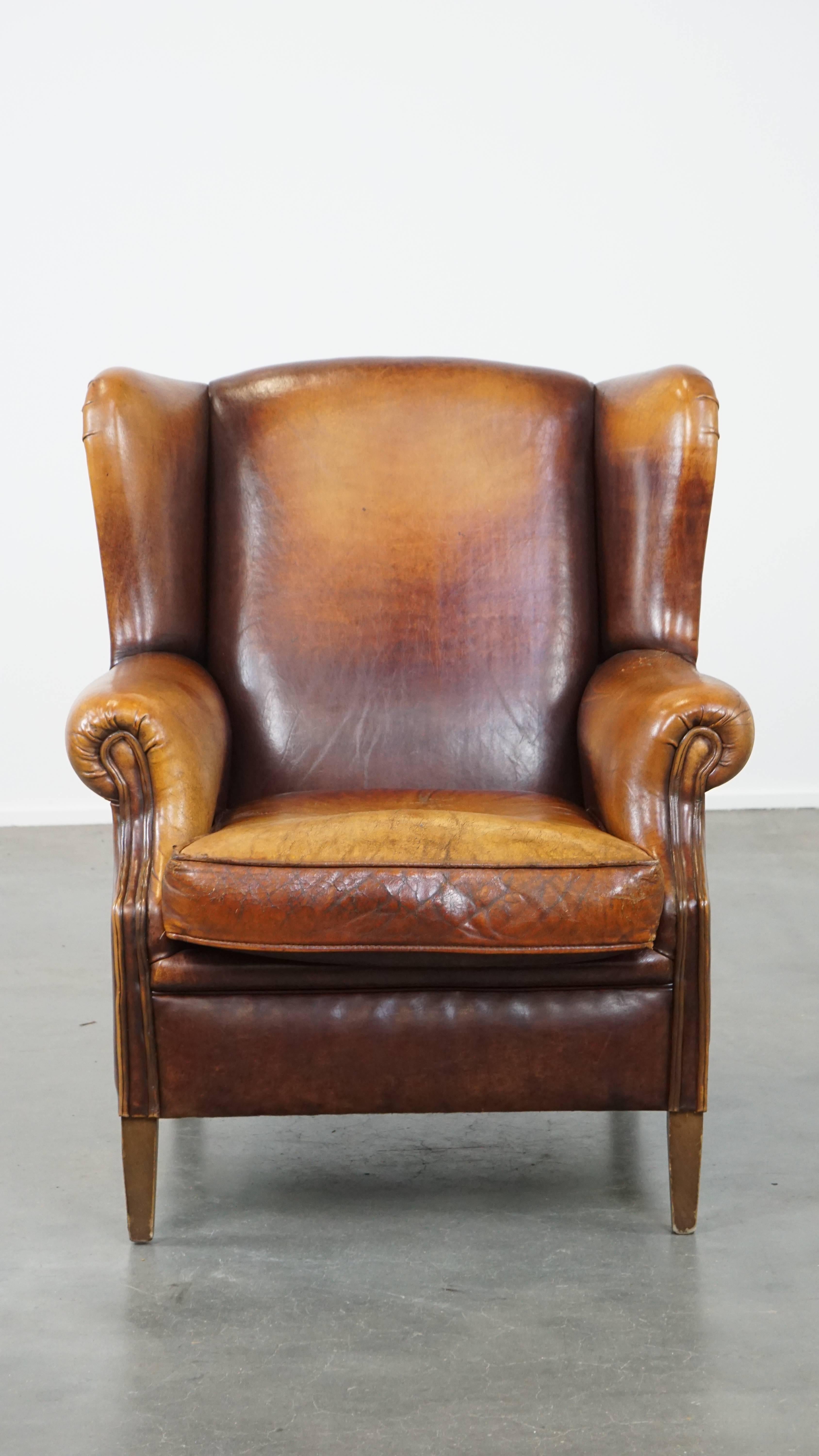 A true eye-catcher with a striking character that will fit into any interior; this is a perfect description of this sheepskin leather wingback armchair. This timeless vintage piece features a beautiful cognac color scheme and is finished with