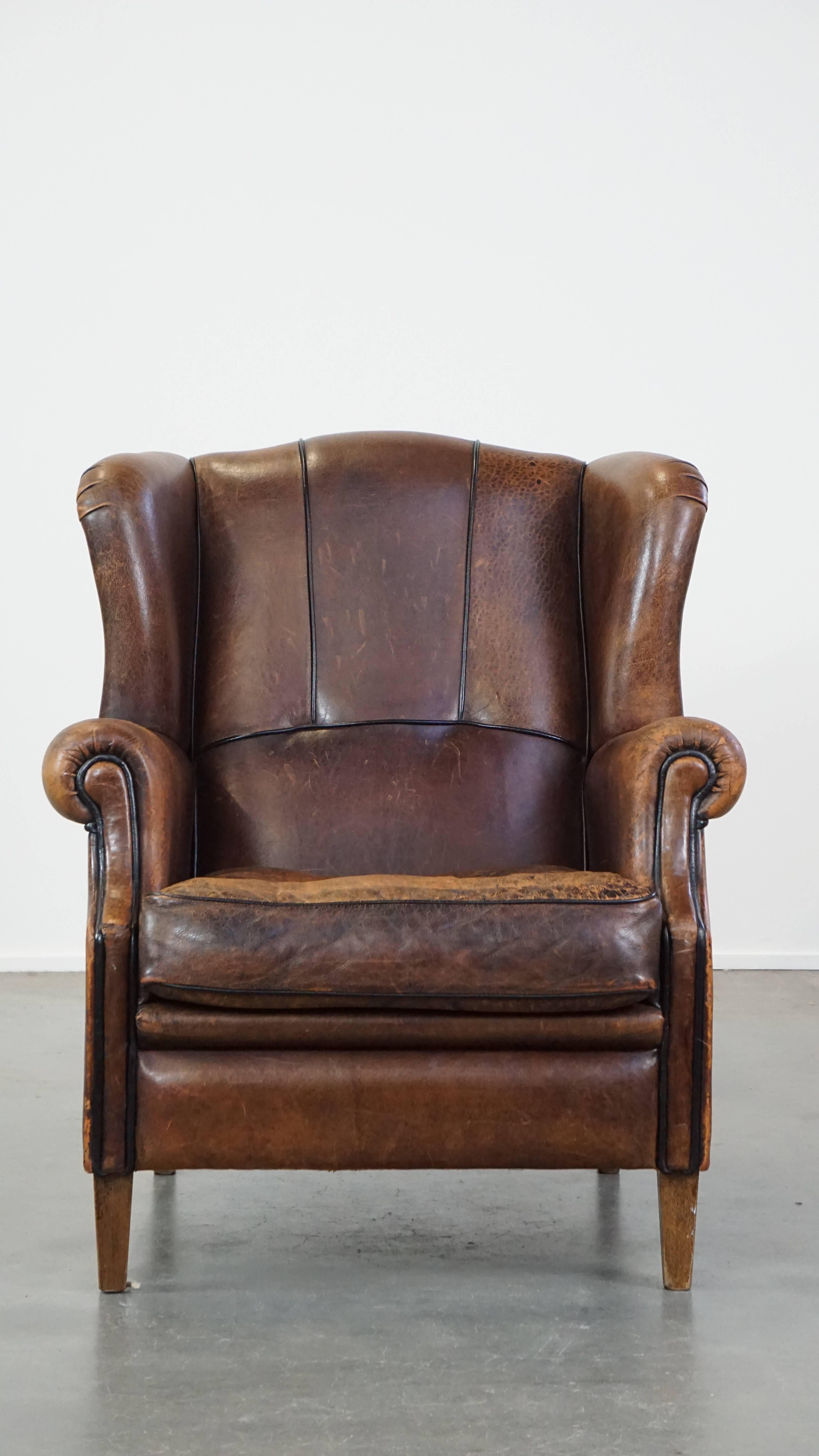 Ce fantastique fauteuil à oreilles en cuir de mouton est plein de caractère et peut facilement être placé dans presque tous les intérieurs. Il a un aspect robuste et majestueux grâce au passepoil du dossier et à sa finition générale. Le fauteuil à
