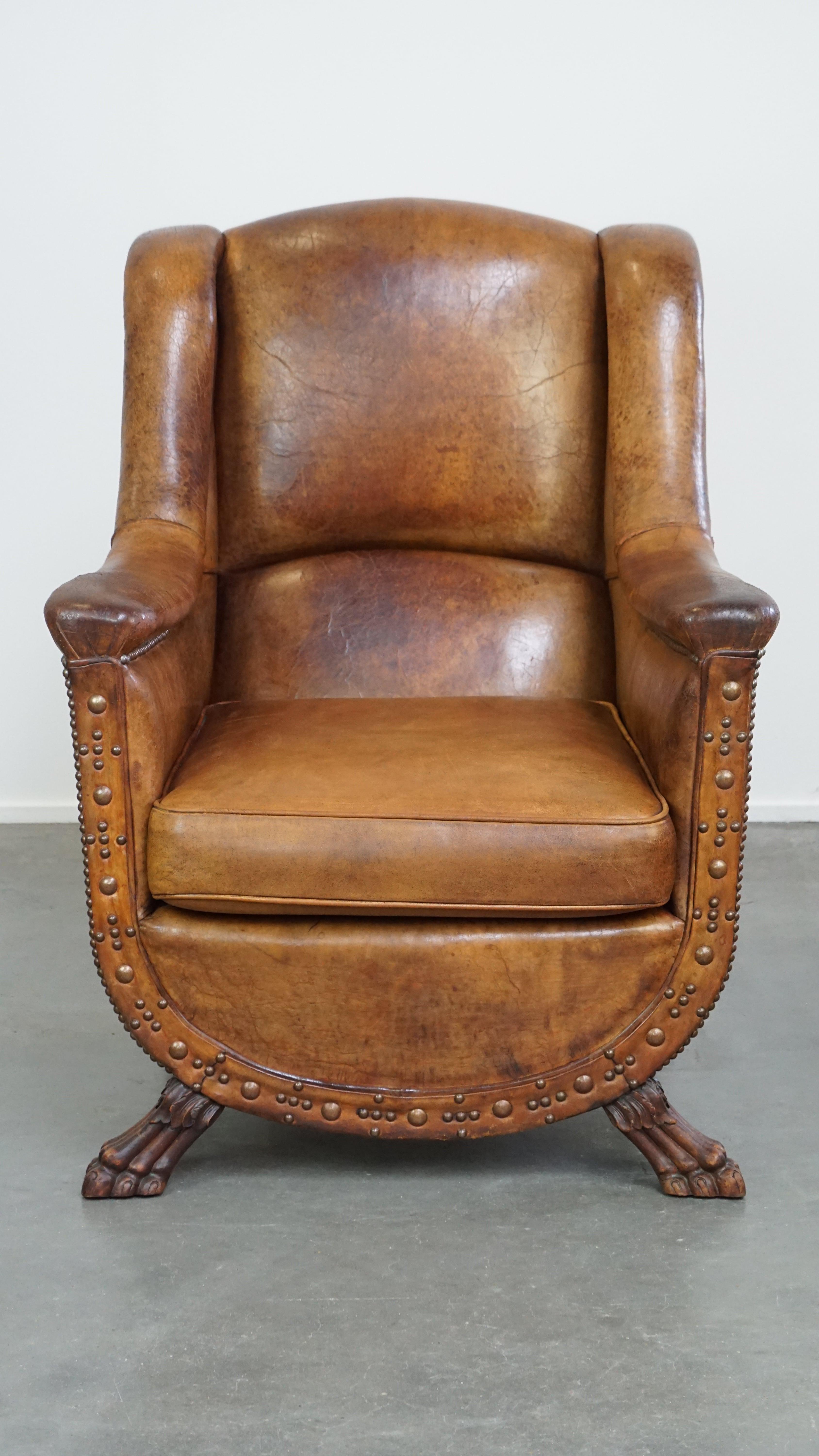 This spacious and comfortable sheepskin leather armchair has an antique frame and was reupholstered with sheepskin leather around 1970. It is finely and uniquely finished with decorative nailheads. Its stylish and bold lion’s paw feet give it a