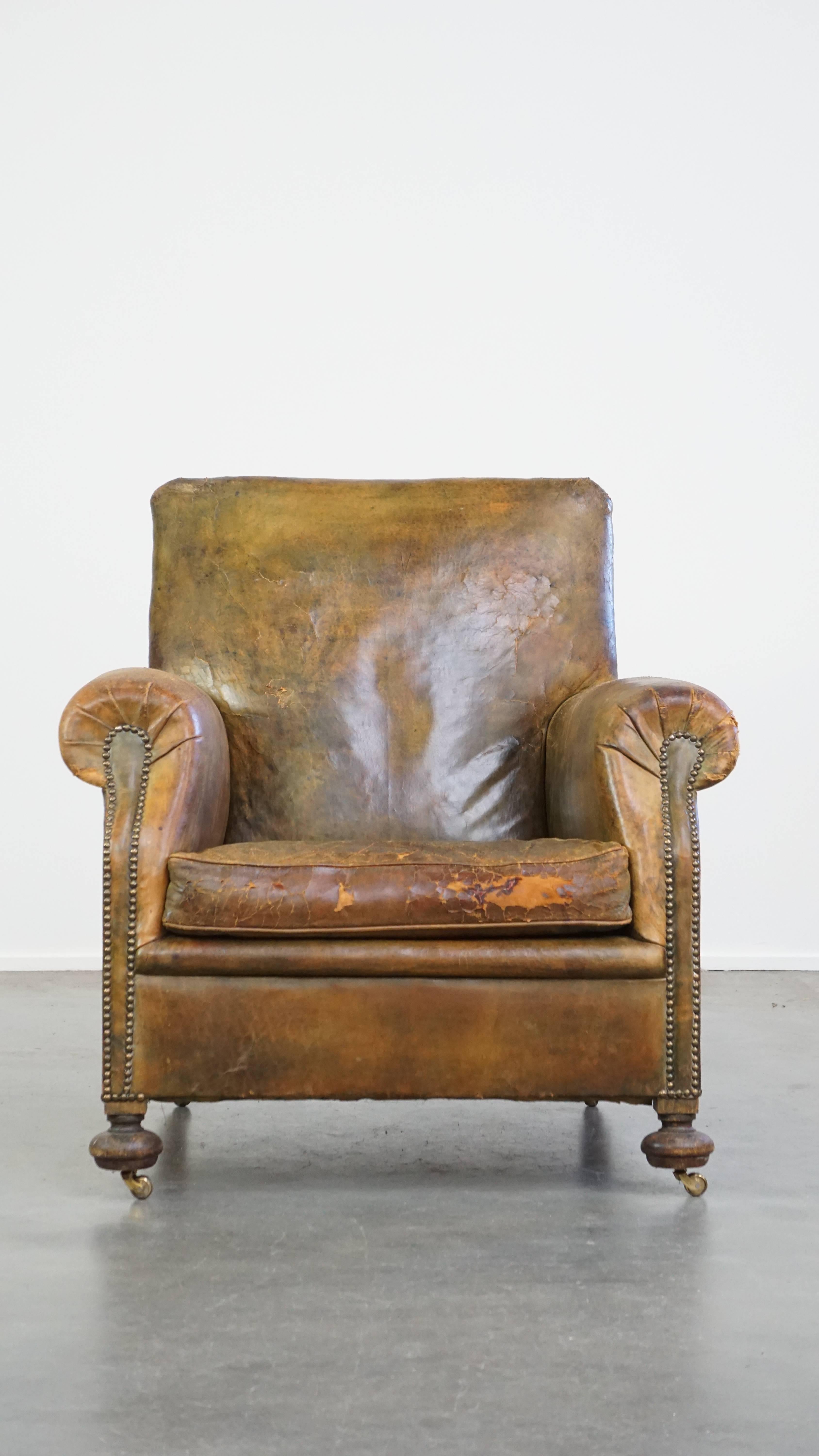 This antique cowhide leather armchair is brimming with character and is, with its unusual color combination, pleasing to the eye. It is equipped with a loose seat cushion and has a comfortable deep seat. Due to its considerable age it has sustained