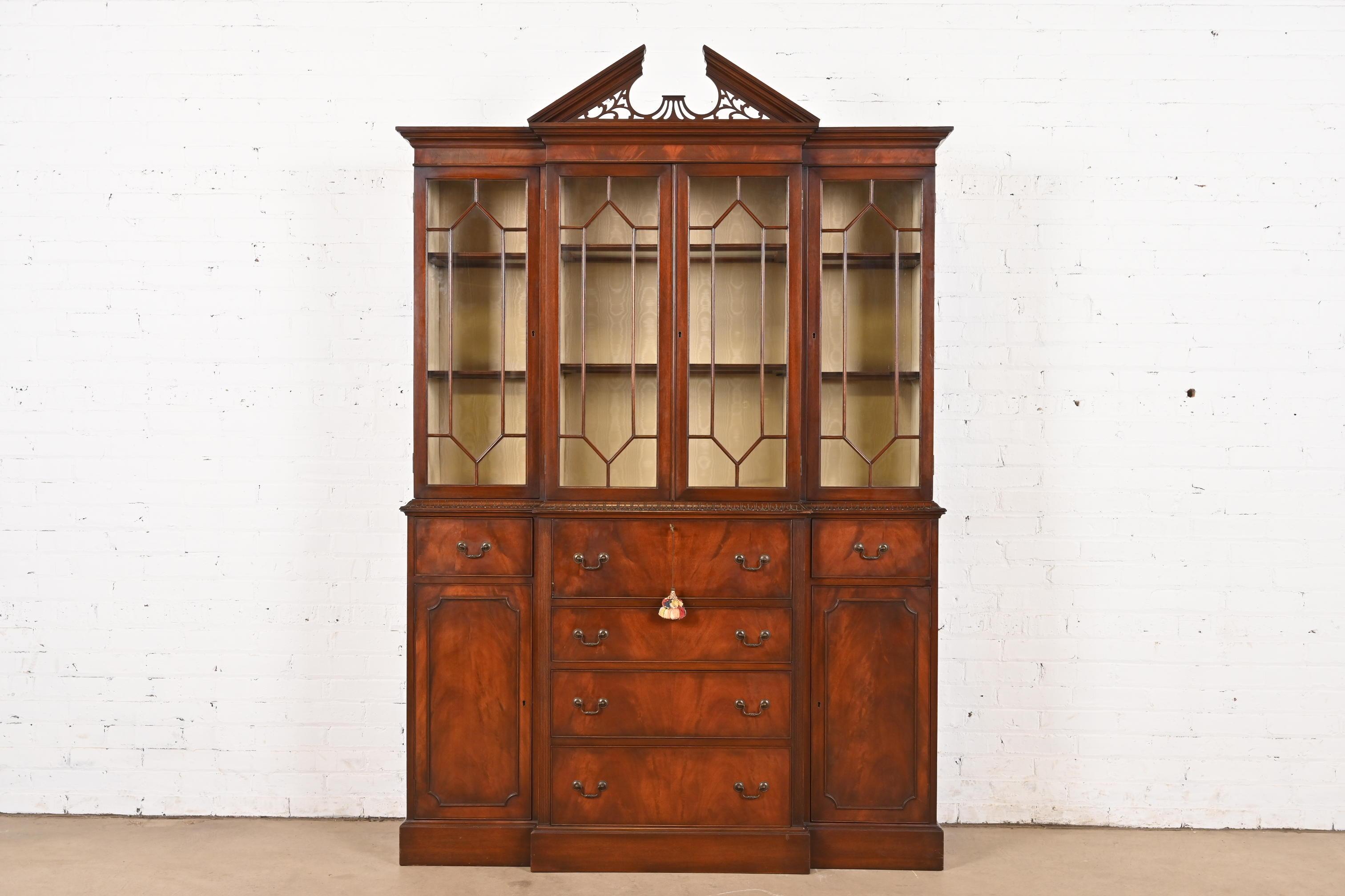 A gorgeous Georgian or Chippendale style lighted breakfront bookcase cabinet with secretary desk

By Charak Furniture Co.

USA, 1940

Stunning book-matched flame mahogany, with mullioned glass front doors, and original brass hardware. Interior
