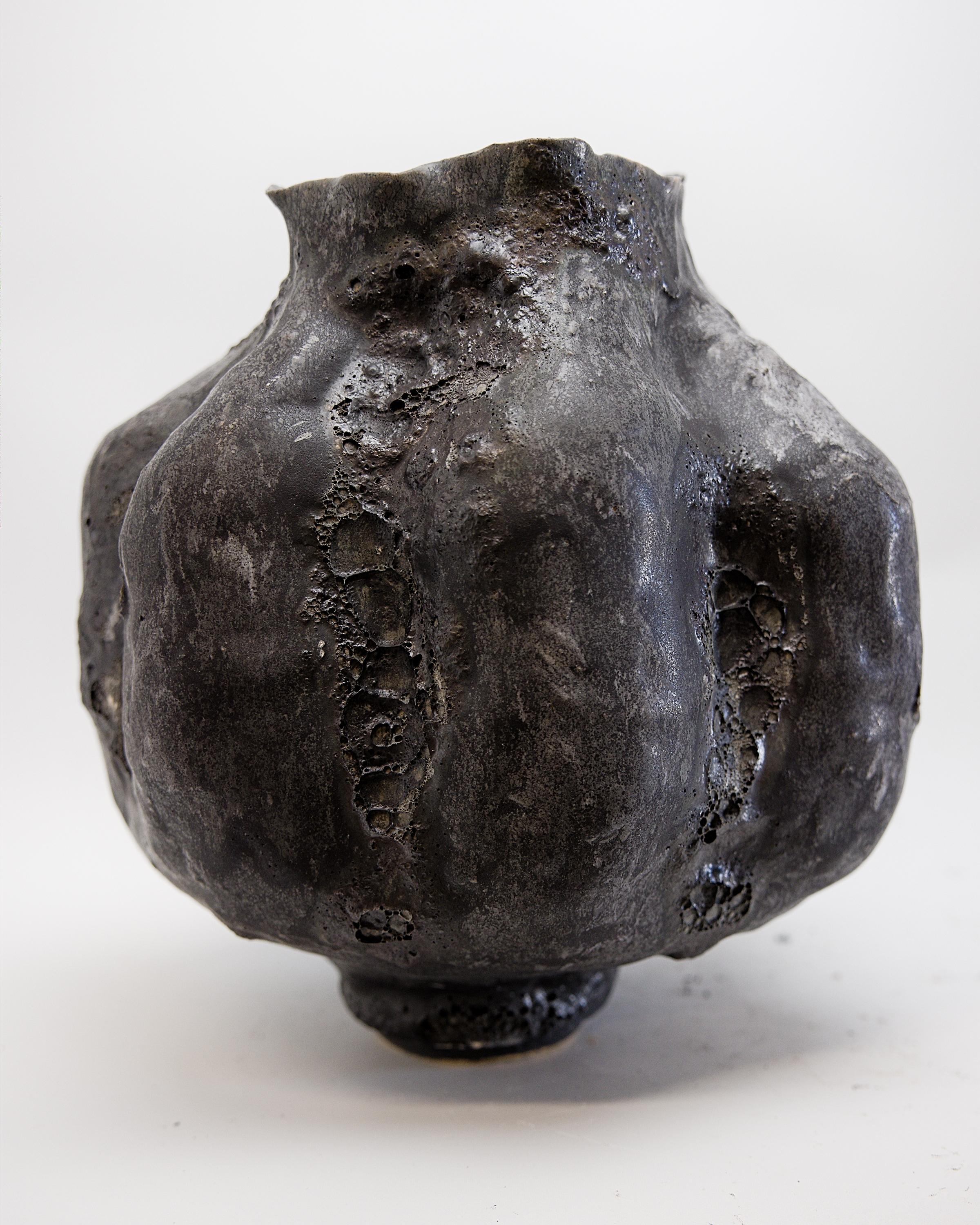 Elevate your interior design project with The Shine Studios' exclusive Black Lava texture Moon Vase II. This dark matte black moon jar features exquisite textures and layers of charcoal, gold, and pigment glazes, creating a truly unique piece. Its