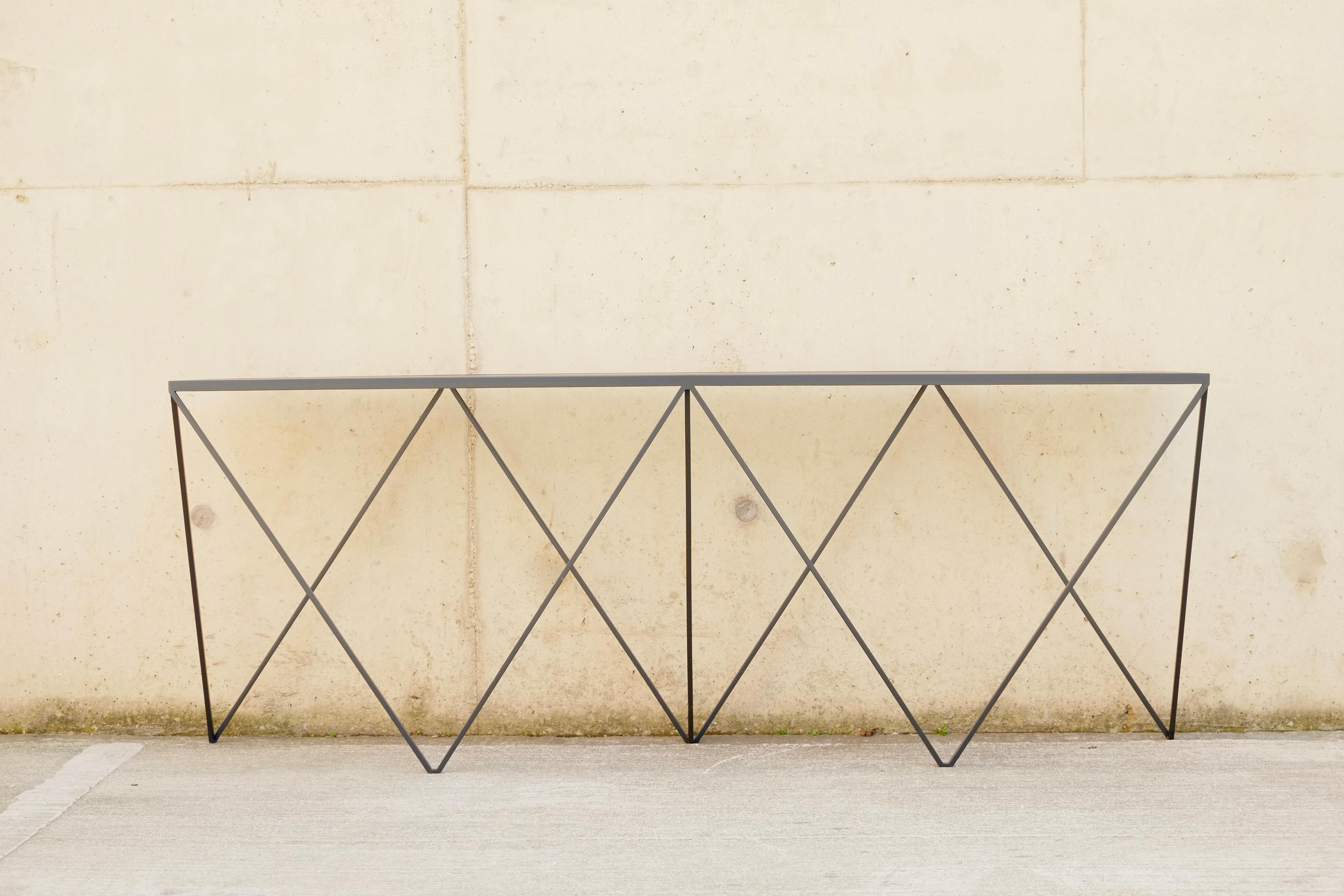 A beautiful long slim Giraffe Console Table made with a powder coated steel frame and a linoleum table top. This piece is finished with a charcoal black frame and a colour matched charcoal linoleum table top. The top is made out of environmentally