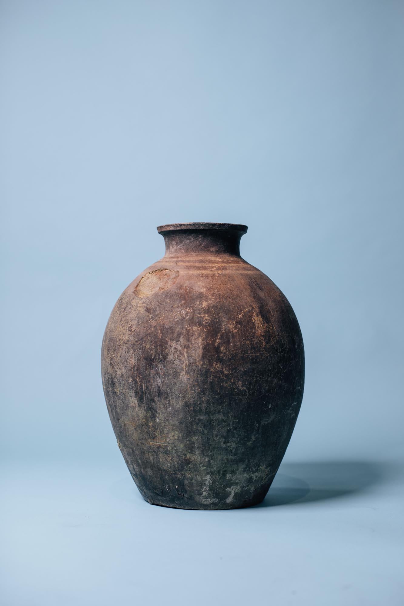 Once used for storing olive oil and grains, this early 20th-century Mediterranean storage jar embodies the understated beauty of utilitarian craft. Hand-thrown from coarse terracotta and wood-fired in traditional kilns, its surface reveals deep