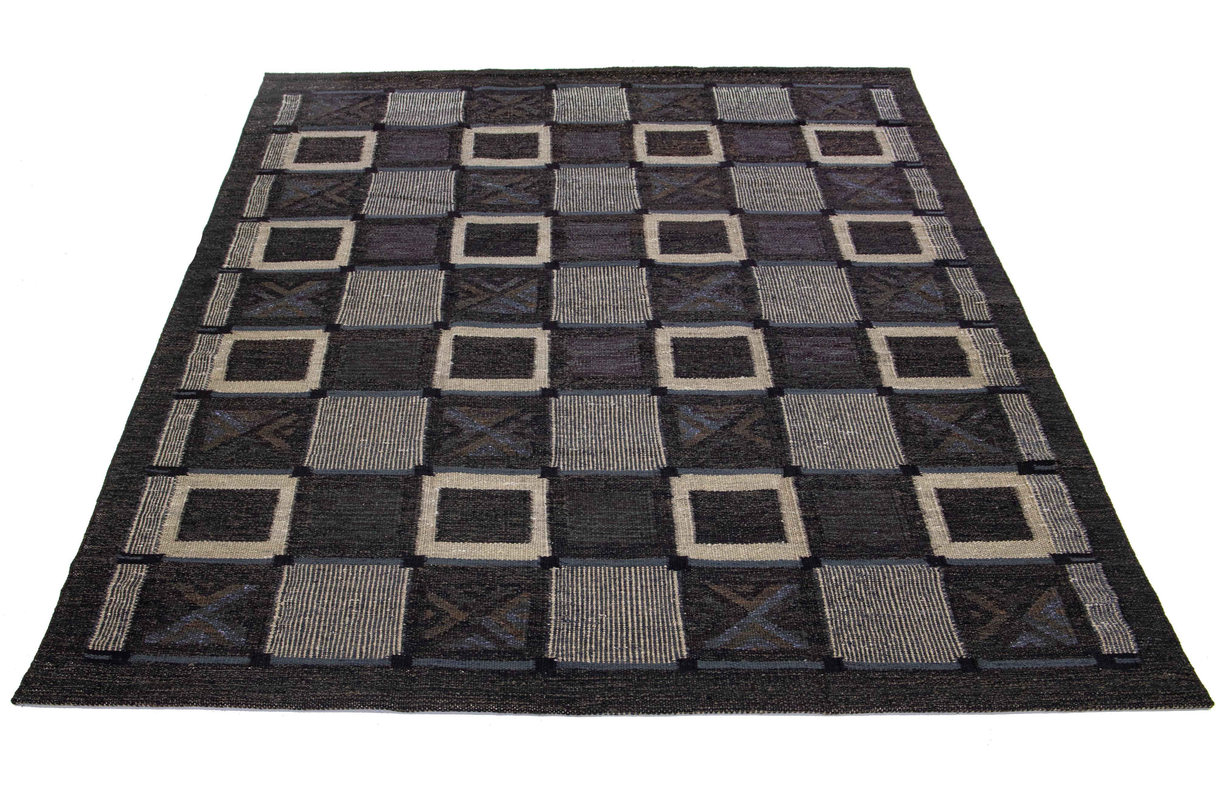 This flatweave rug features a modern Swedish design with a charcoal base. It is complemented by gray-blue, beige, and brown geometric patterns throughout the design.

 This rug measures 8'10