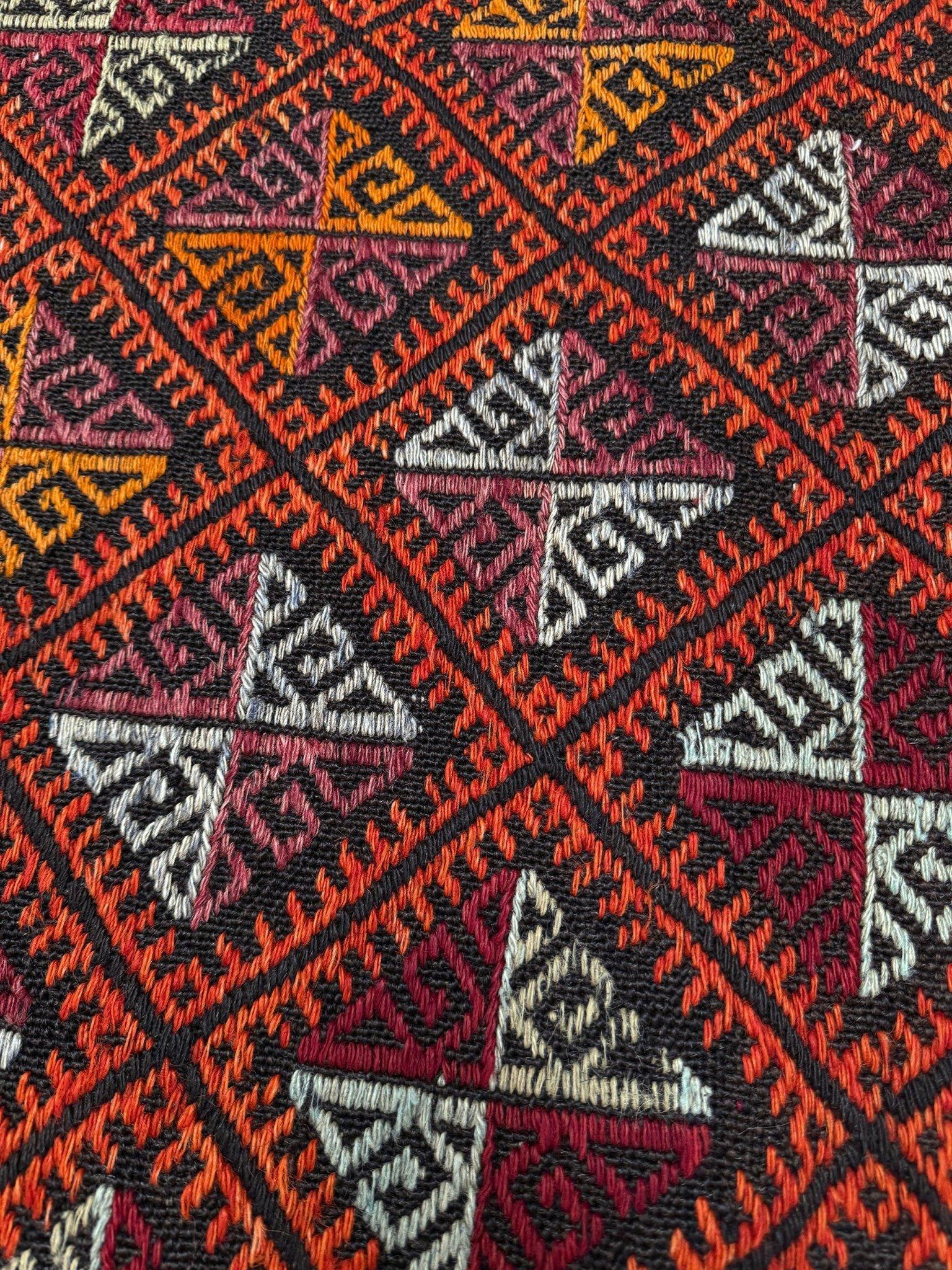 Ce kilim Malatya Cicim de Turquie, tissé dans les années 1960, incarne l'art audacieux de la broderie anatolienne. Tissé à la main à partir de laine filée, il présente une broderie complexe en cicim (relief) formant un treillis de diamants - chacun