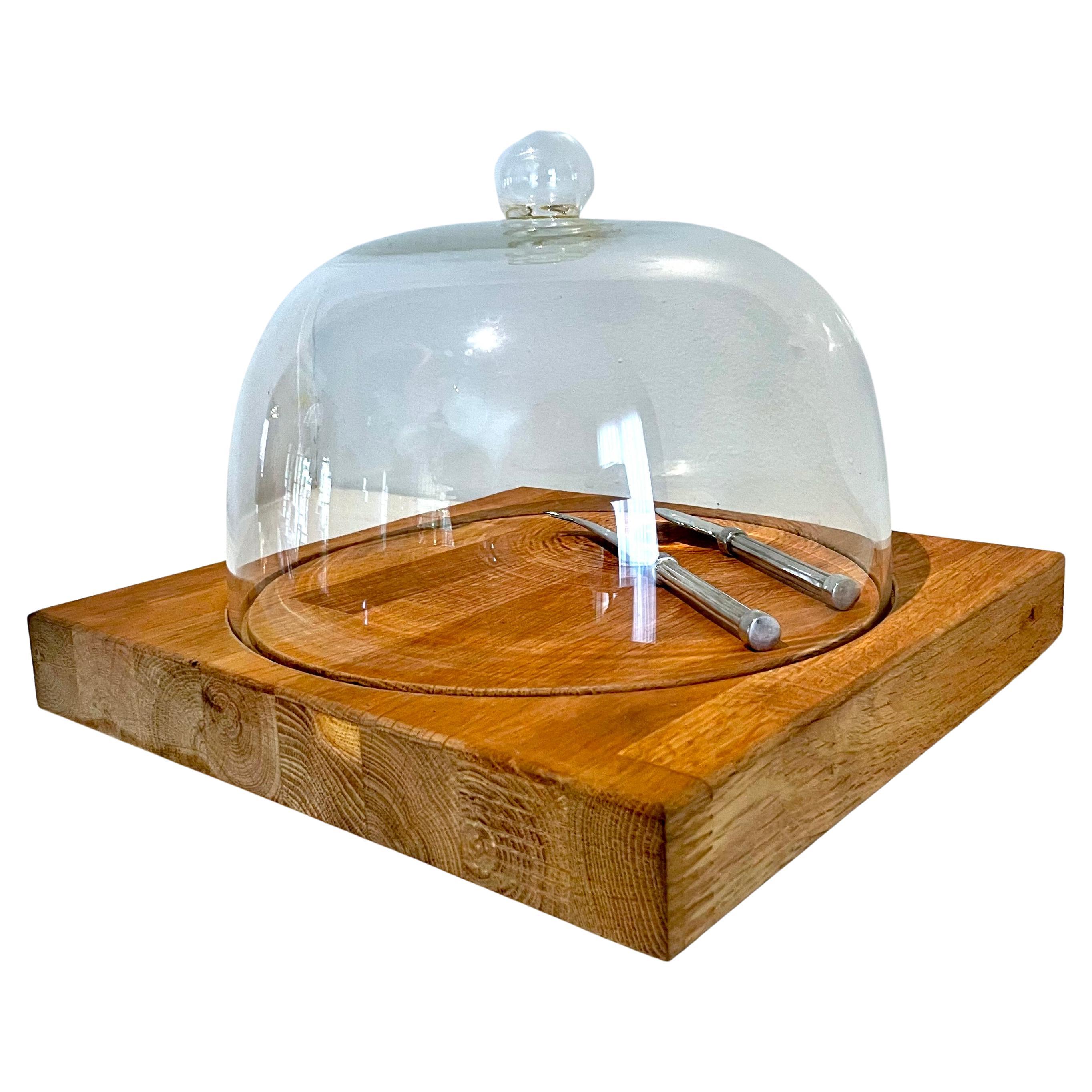 Cheese or charceuterie plate with glass domed lid and silver serving utensils. The glass lid fits securely into a groove carved into the wooden base. The silver serving set have pinstriped handles for some mid-century modern influence. 

A beautiful
