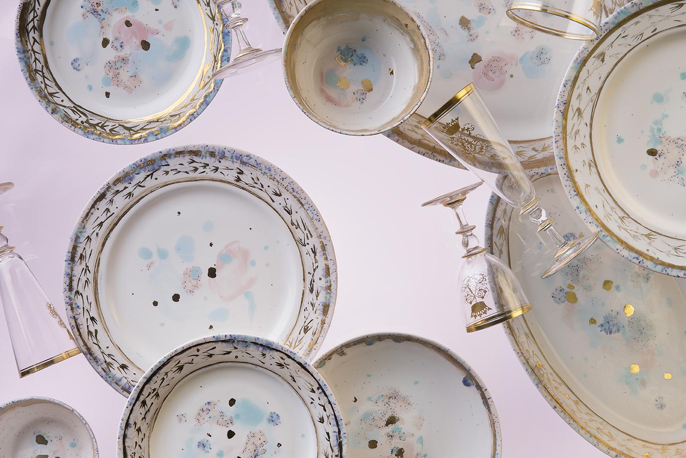 Hand painted in Italy from the finest porcelain, this Dafne Rim Charger has a narrow pink and blue dotted rim surrounding a broad, delicate golden decor of stylized flowers; subtle light blue and pink brushes sprinkled with black powder float on the