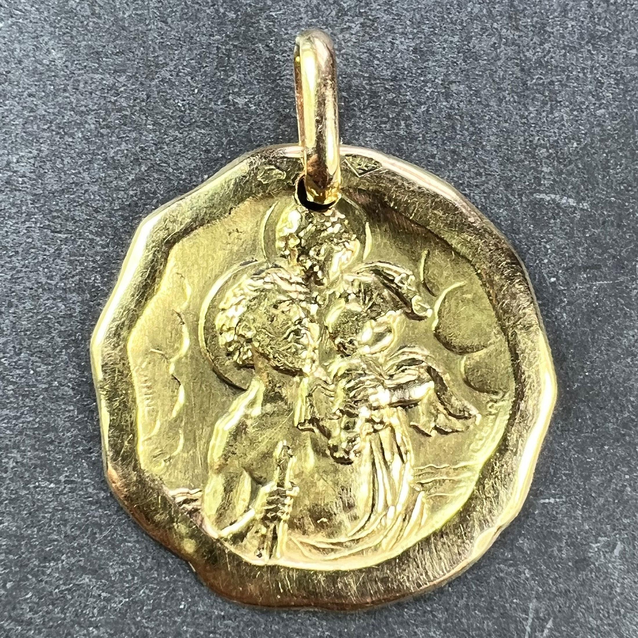 A French 18 karat (18K) yellow gold charm pendant or medal designed by Charl for Sanne depicting St Christopher carrying the infant Christ across the river. Stamped with the eagle's head for French manufacture, Sanne's makers mark, and signed Sanne