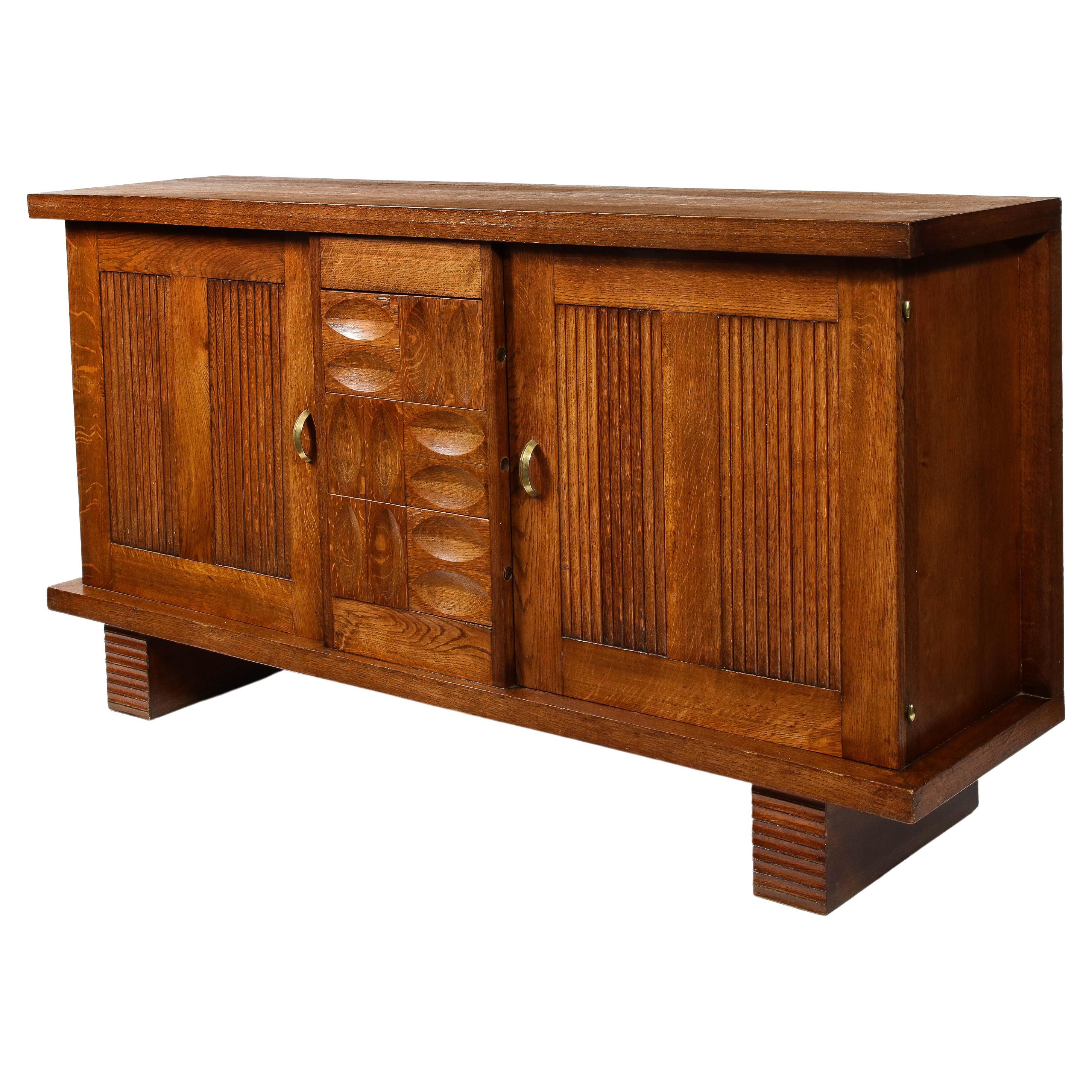 An exceptional credenza by Charles Dudouyt in oak. There are many unique details on this very well-proportioned piece. A stand out is the concealed drawer release mechanism— a little button hidden on the side of each drawer that unlocks them— an