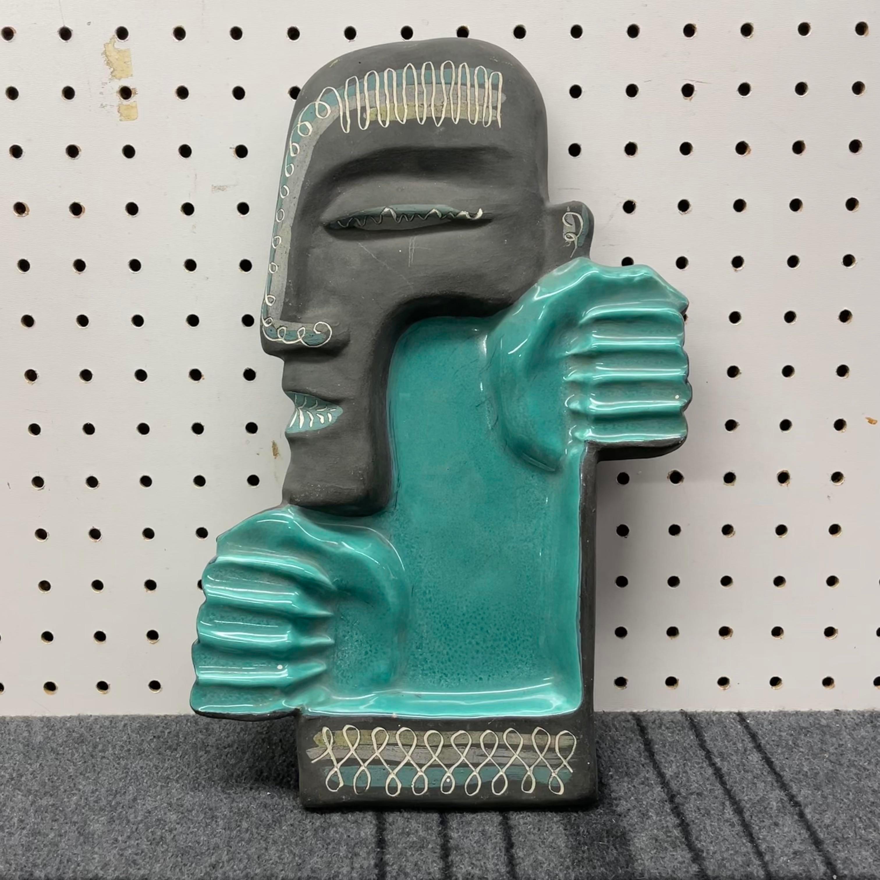An amazing mid-century tiki ashtray by artist duo Charles and Alice Smith. The piece has an incredible tiki head design with grey matte pottery and teal glaze. It is signed on the bottom 