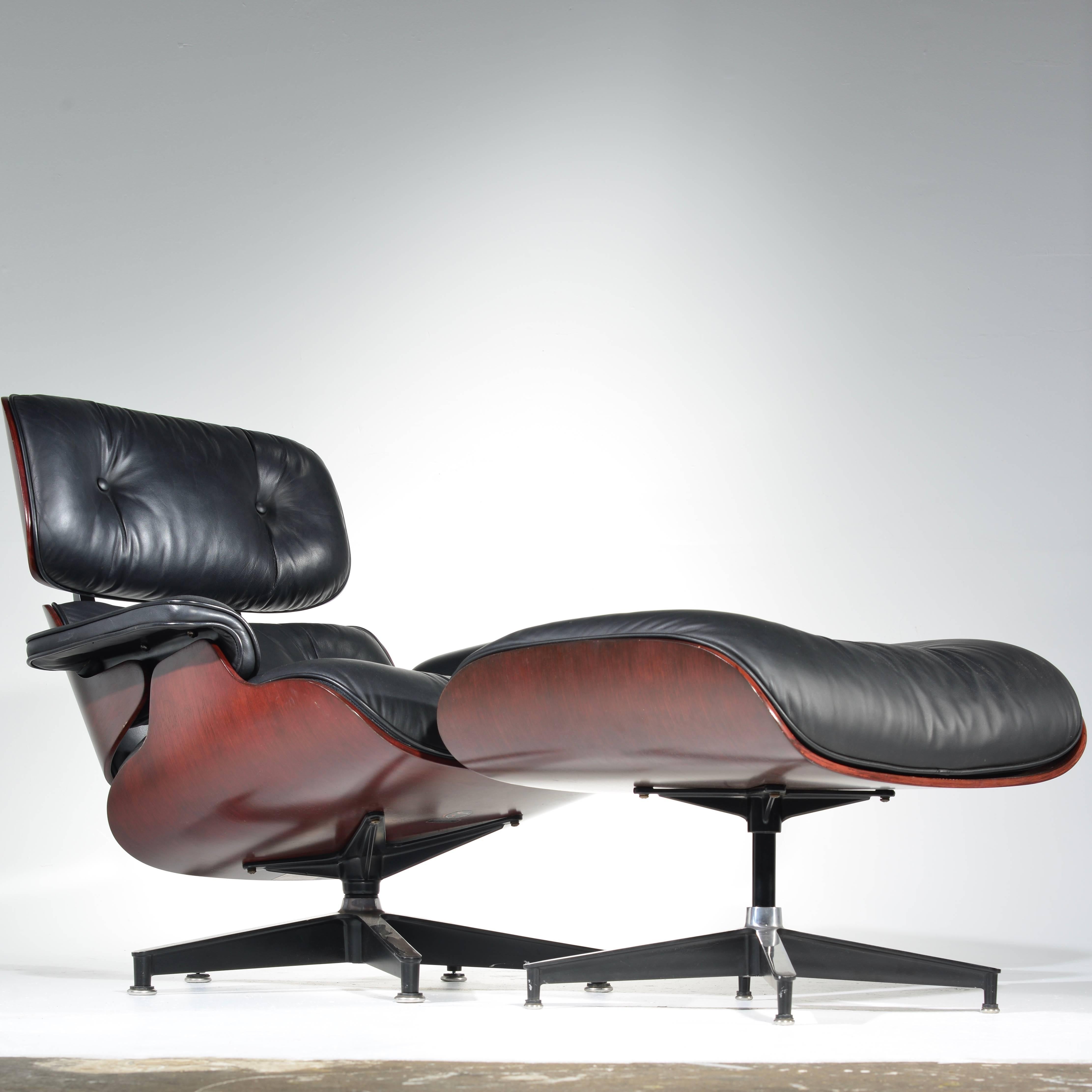 670 lounge chair and 671 ottoman designed by Charles and Ray Eames for Herman Miller. This iconic piece features a cherry shell and original black leather upholstery.