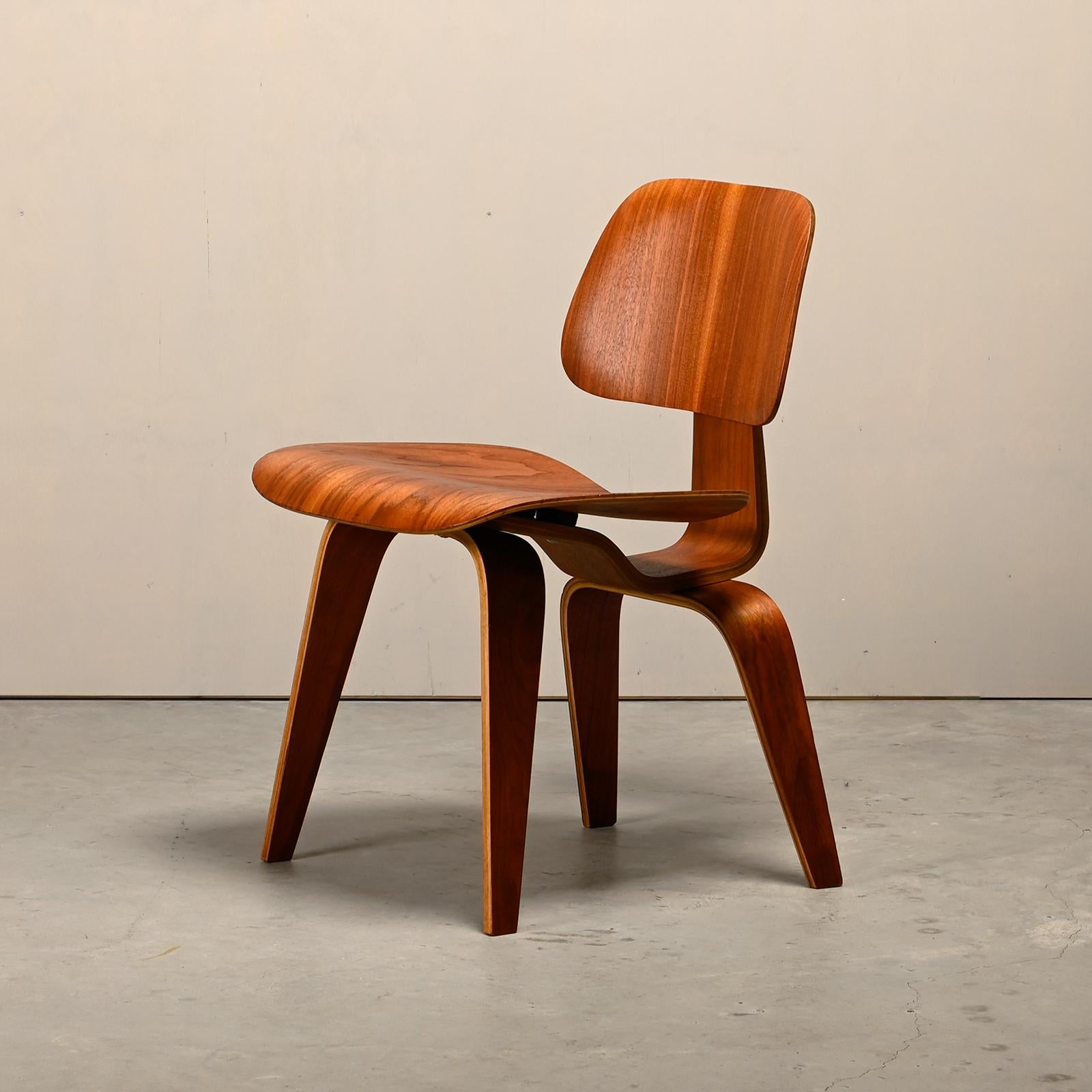 Iconic DCW dining chair in walnut. Early Evans Products Company, Molded Plywood Division production from 1949 (5-2-5 screw configuration). The chair is in good vintage condition with visible wear and aging (light scratches and minor veneer damage).