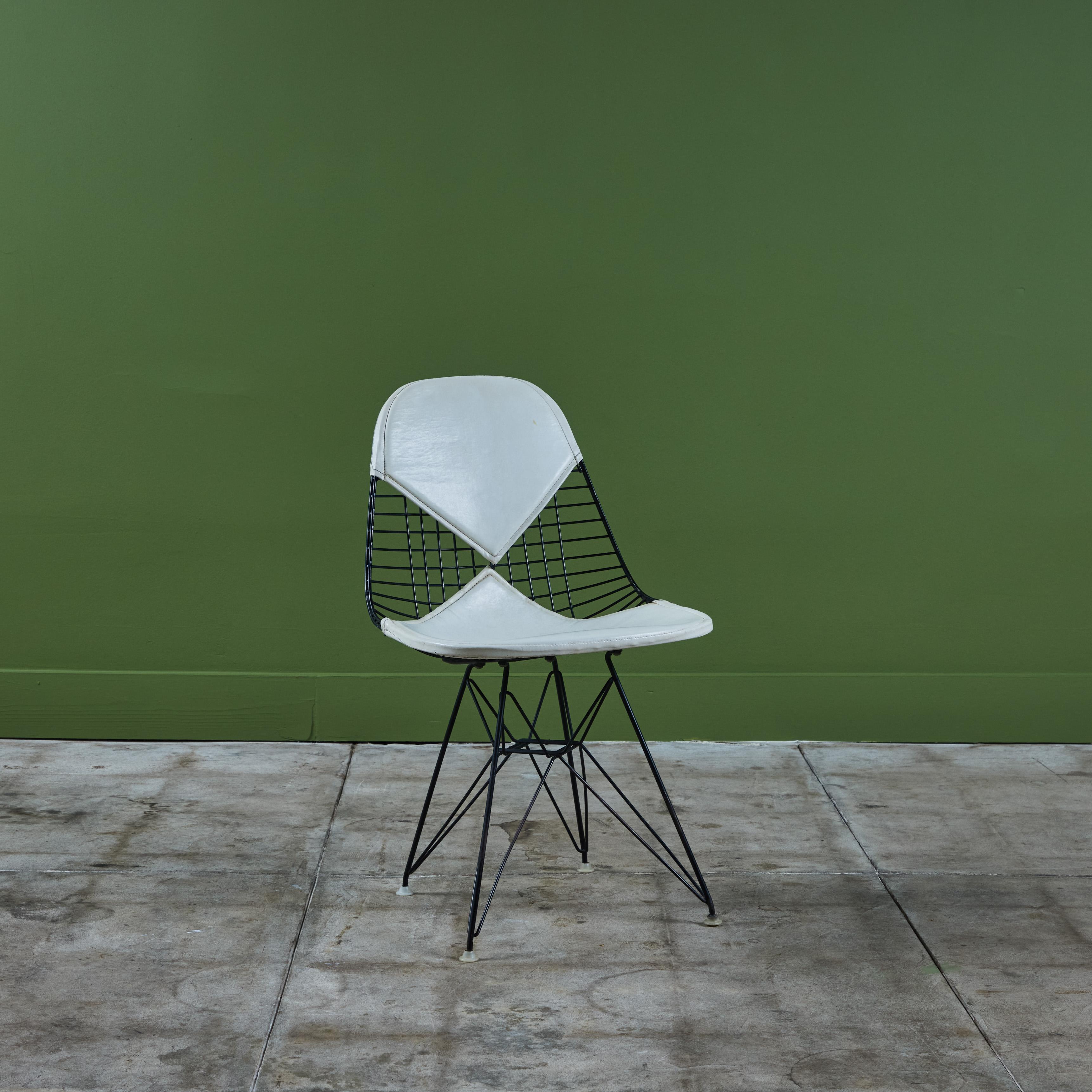La silla DKR-2 de Charles and Ray Eames para Herman Miller, también conocida como la silla bikini, tiene un cojín de asiento de Naugahyde blanco y un respaldo que recuerda a un bikini. La silla tiene un armazón de metal negro con base de pata de