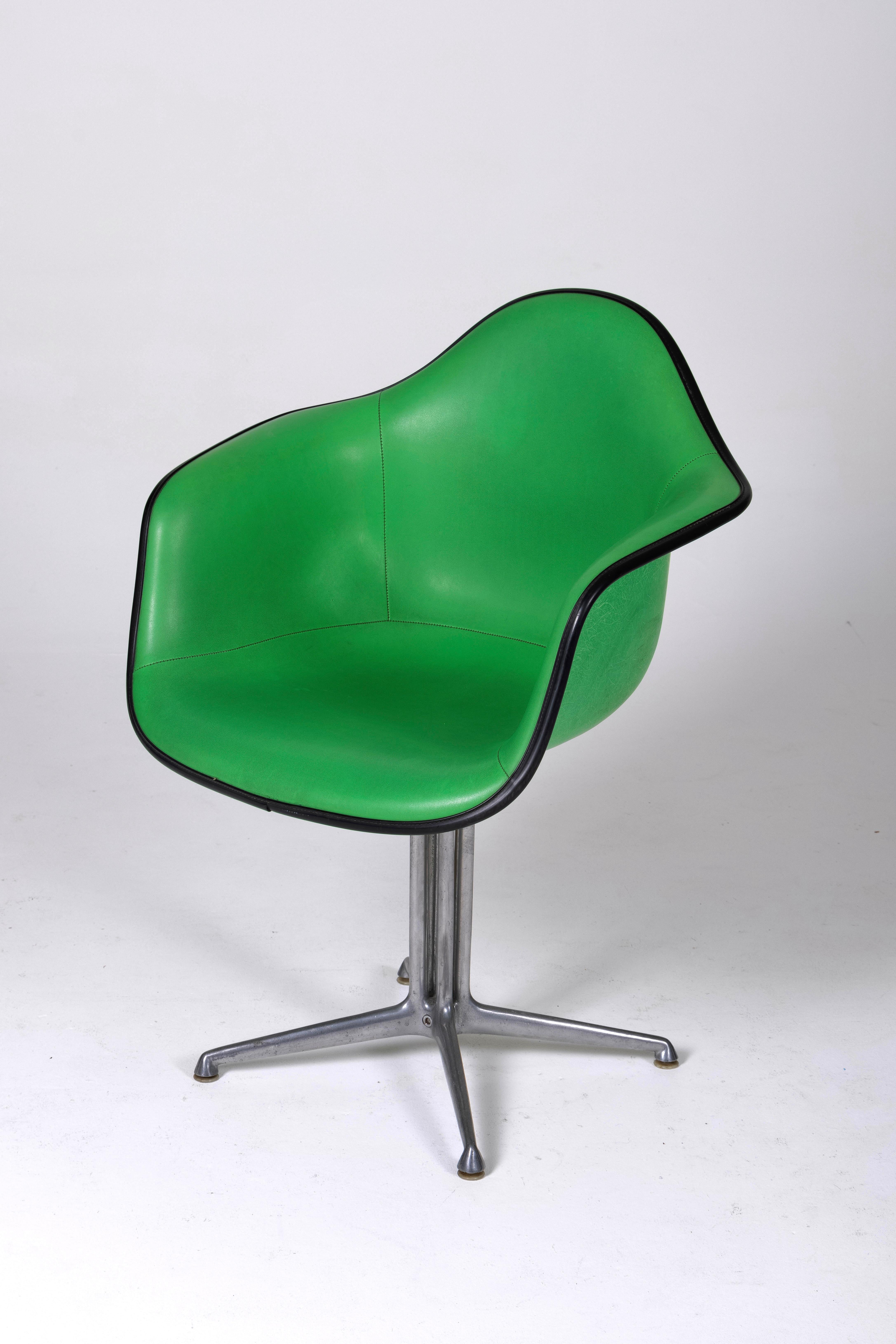 Iconic 'Eames Plastic Chair' by Charles and Ray Eames from the 1950s. This chair, or office chair, features a green leather seat and backrest, with the back of the backrest made of green polymer. The base is made of chromed metal. Scratches are