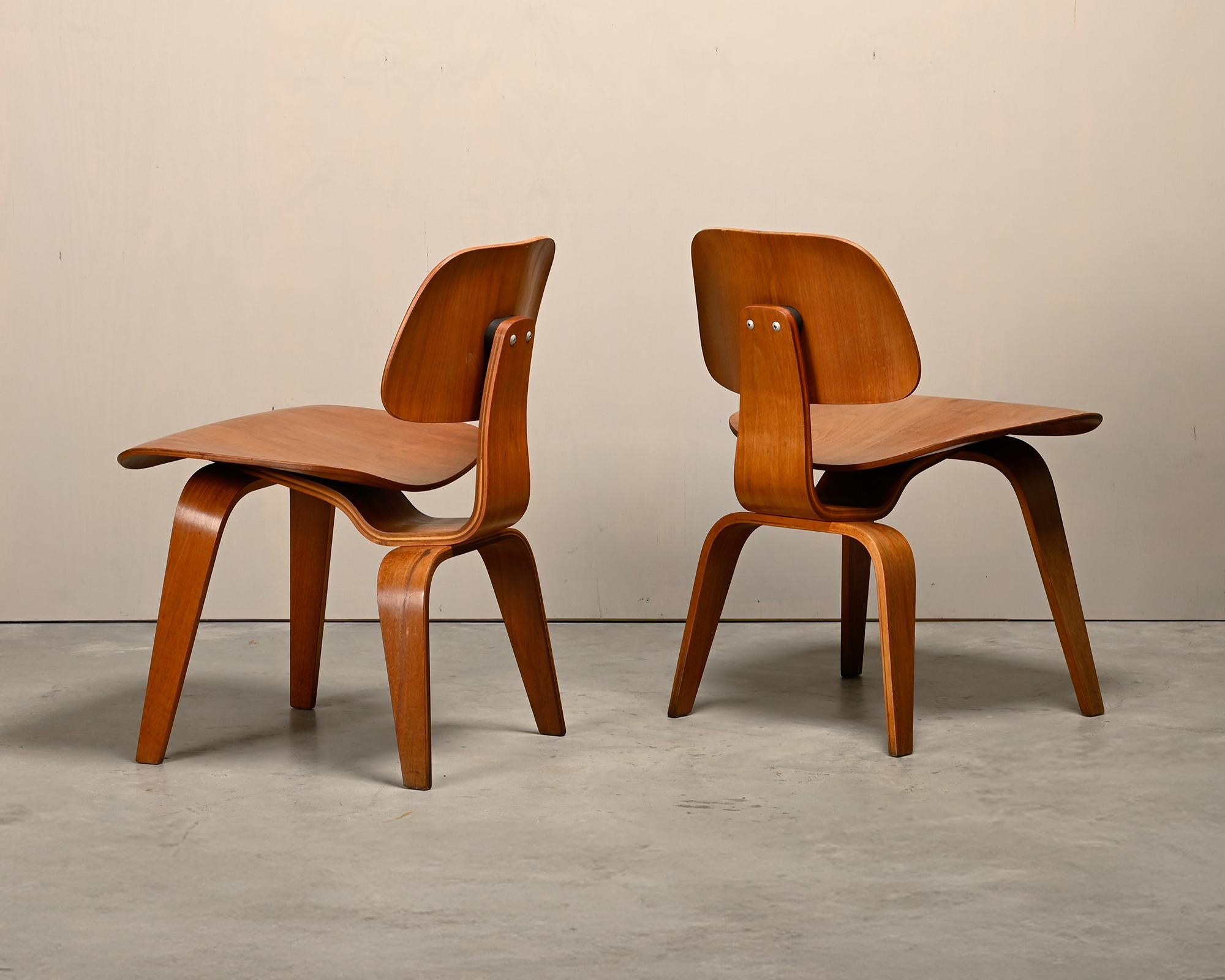 Iconic pair DCW dining side chair in Walnut plywood. Early Herman Miller production from the fifties (4-2-5 screw configuration), just after Herman Miller took over production from Evans Products Company, Moulded Plywood division. The chairs are in