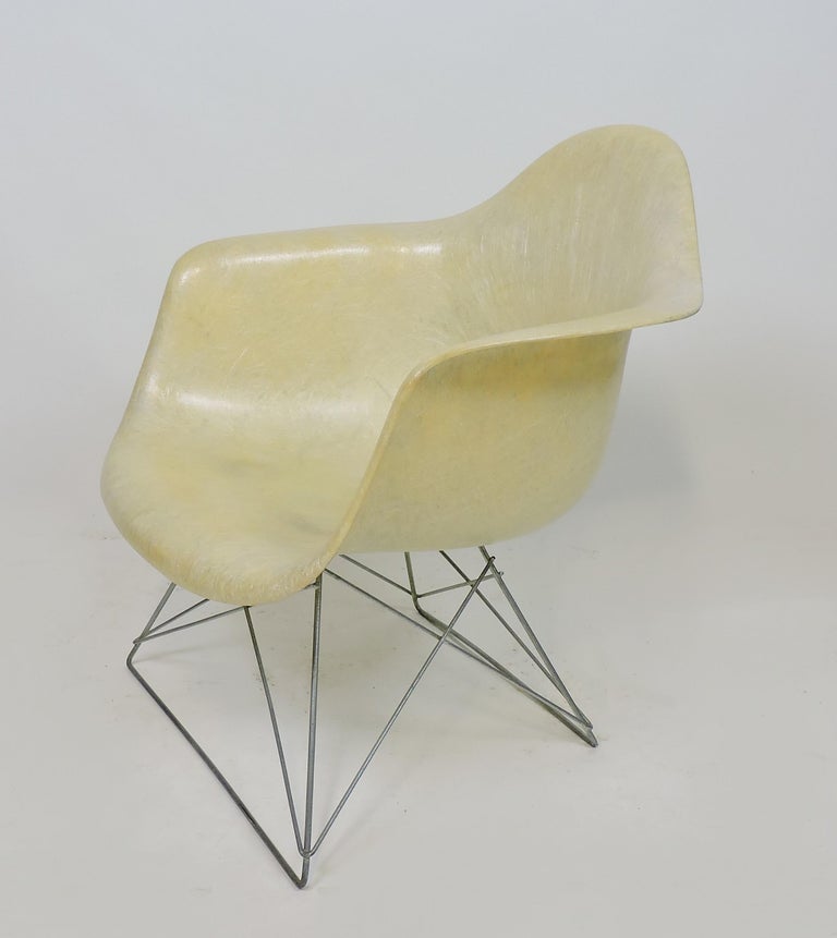 Hard to find 1st generation LAR (Low armchair on rod) shell chair designed by Charles and Ray Eames and manufactured between 1950-1953. This chair is in the parchment color, has a rope edge and a zinc cat’s cradle base. Labeled with a partial early