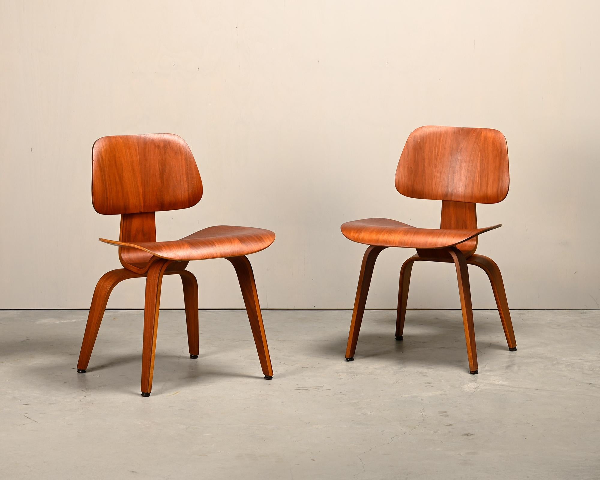 Iconic pair DCW dining side chair in Walnut plywood. Early Herman Miller production from the fifties (5-2-5 screw configuration), just after Herman Miller took over production from Evans Products Company, Moulded Plywood division. The chairs are in