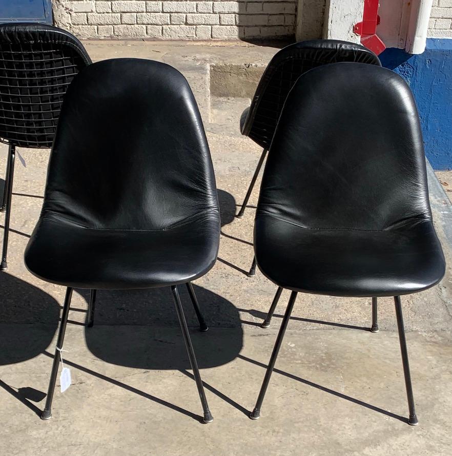 Charles and Ray Eames for Herman Miller DKX-1 chairs, set of four, black leather, H-base, circa 1954,
Boot glides 
The abbreviated Eames DKX chair, part of the Wire Mesh Series, stood for Dining (D) height, K-Wire (K) chair on X-base (X). As with