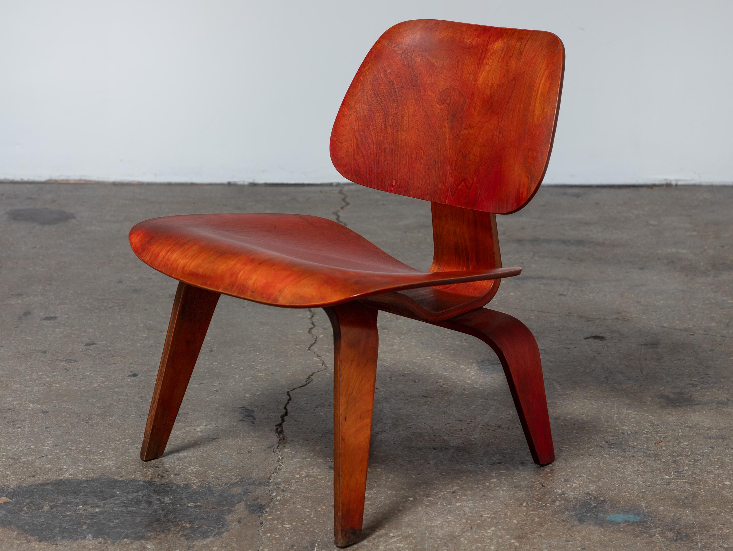 Chaise longue LCW, teinte à l'aniline rouge, conçue par Charles et Ray Eames et fabriquée par Herman Miller. Le bois teinté à l'aniline est vibrant et riche, mettant en valeur le grain spectaculaire du dessous. La finition d'origine est intacte et