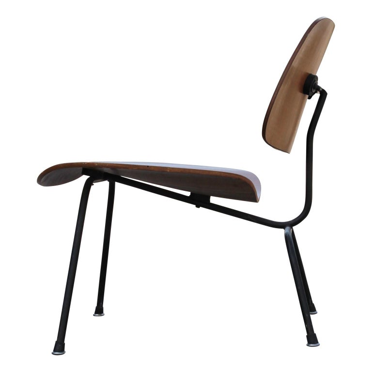 A walnut classic LCM chair by Charles and Ray Eames for Herman Miller. The chair features a steel frame with a curved plywood seat and backrest. The piece has a thick plywood middle section indicative of the early 1950s model. Originally had foil