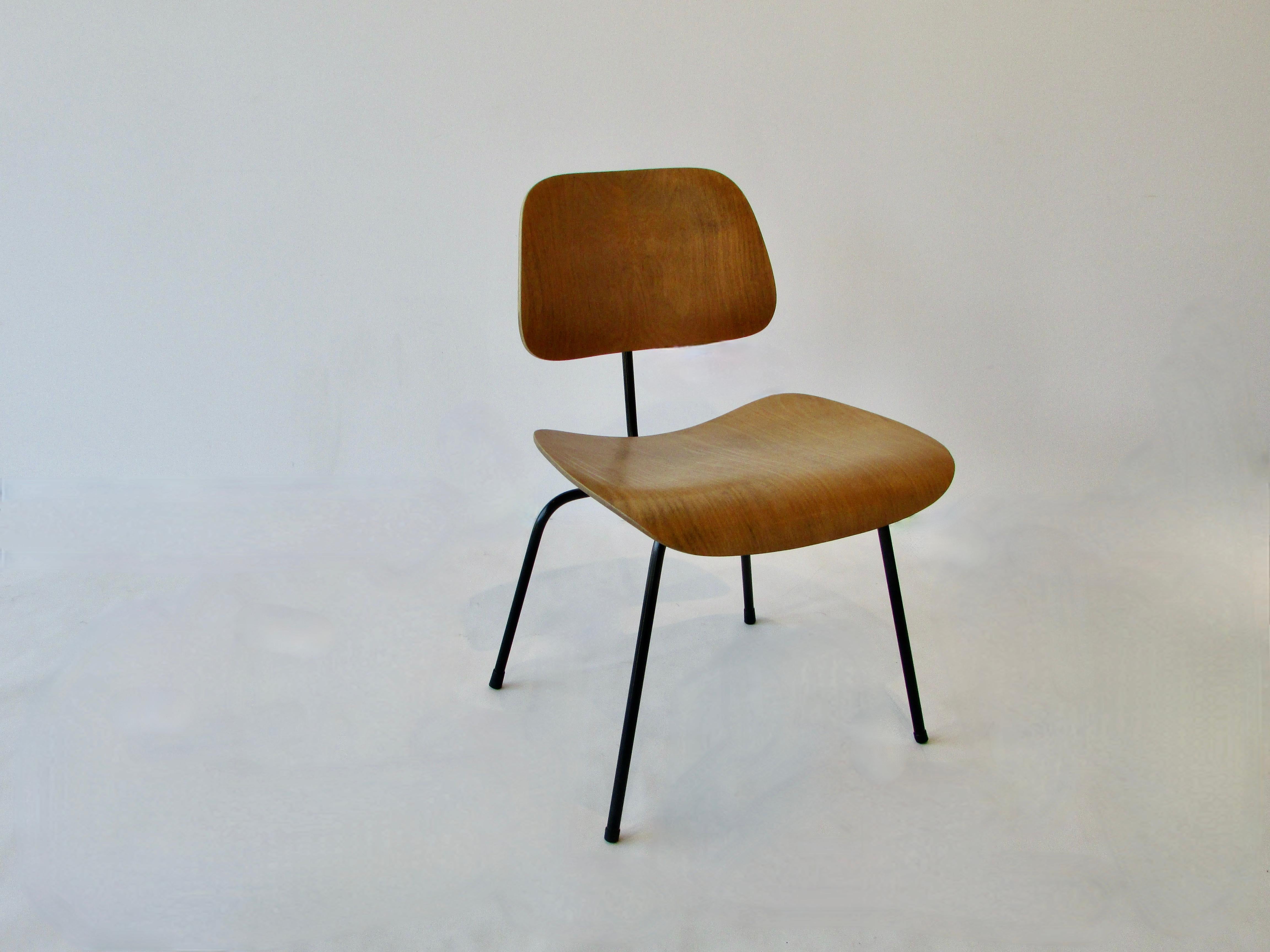 Charles and Ray Eames dining chair metal ( DCM ) for Herman Miller. Blonde laminate plywood seat in original finish on recently matte black powder coated wrought iron frames.