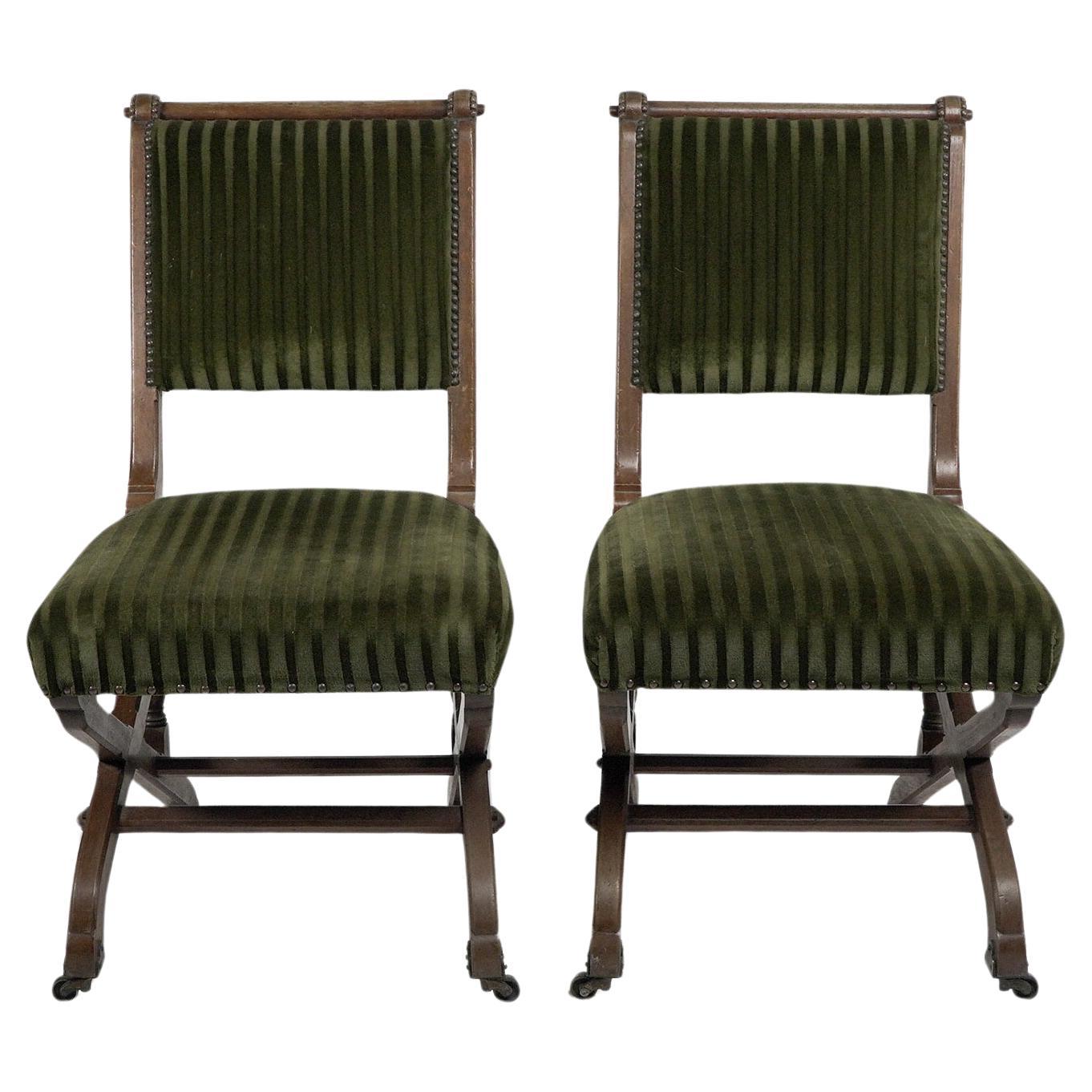 Charles Bevan under licence to Marsh Jones & Cribb. A pair of Gothic Revival side chairs, with pegged oak frame and scissor style legs on the original decorative brass and ceramic casters. They follow the design of Bevans 'New Registered Reclining