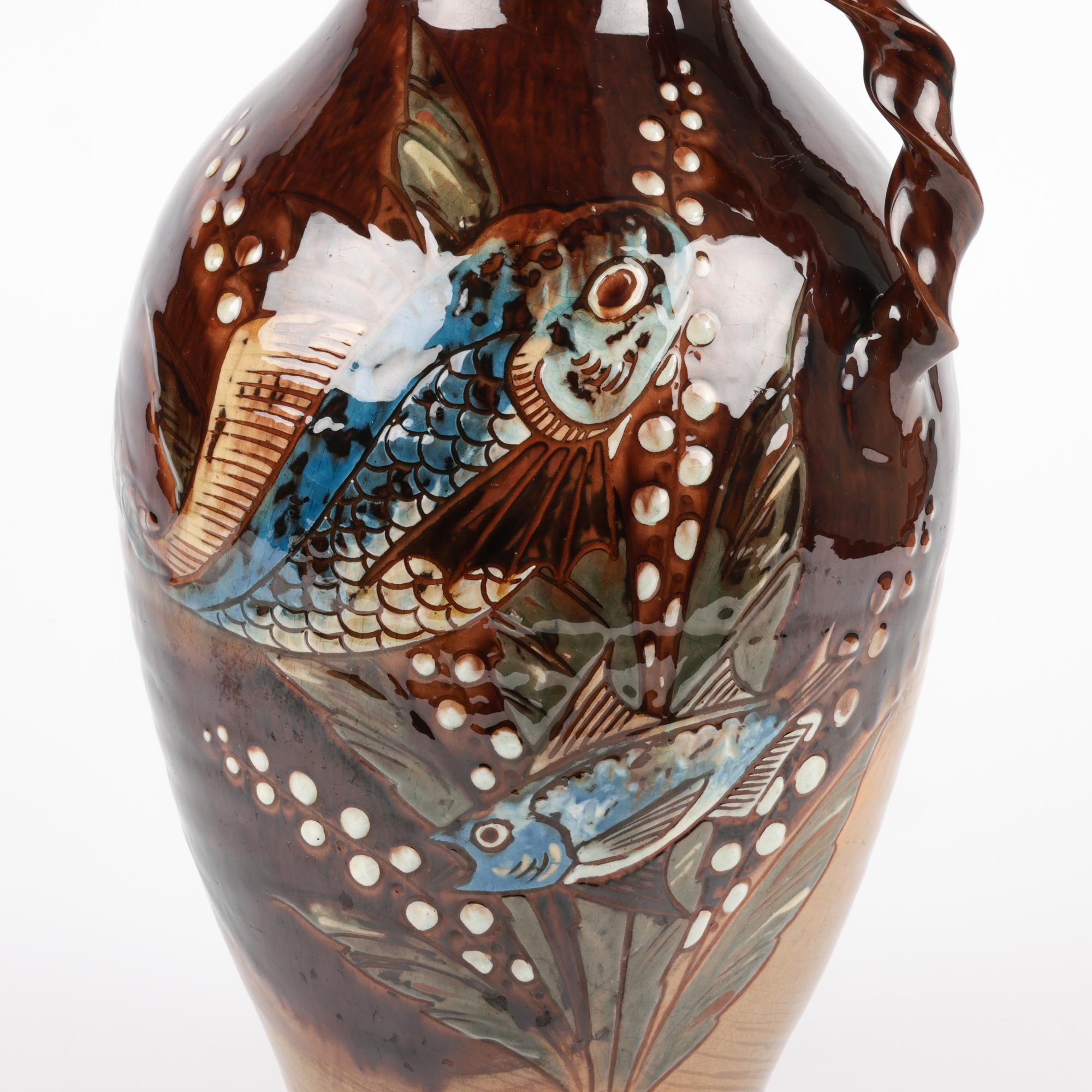 Une superbe grande cruche à anse en poterie d'art de Charles Brannam, de forme flagon, avec des sgraffites en bas-relief de poissons nageant, réalisés par William Baron et datés de 1890. Cette élégante cruche en faïence repose sur une base plate et