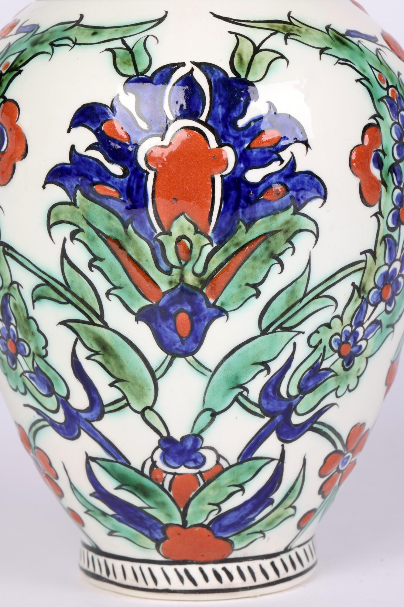 Superbe vase en poterie d'art belge peint à la main, décoré de motifs floraux de style islamique, attribué à Charles Catteau et datant d'environ 1920. Le vase, de forme bulbeuse arrondie, repose sur un pied rond étroit avec un sommet étroit en forme