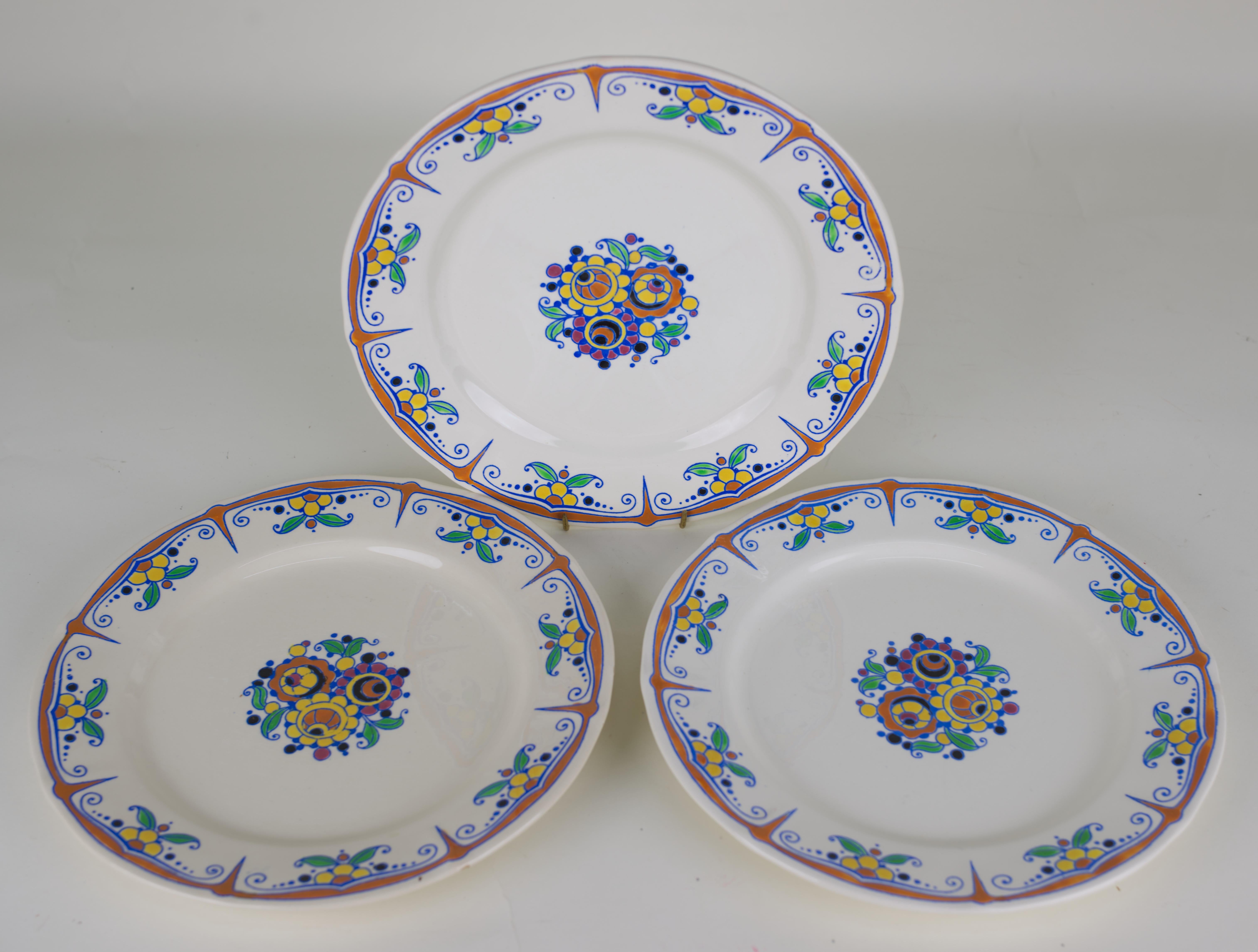 Three extremely rare faience dinner plates are hand-painted on ecru background with Art Deco style orange and yellow flowers and green leaves. This design was widely used on various vases signed by Charles Catteau; there are multiple examples in