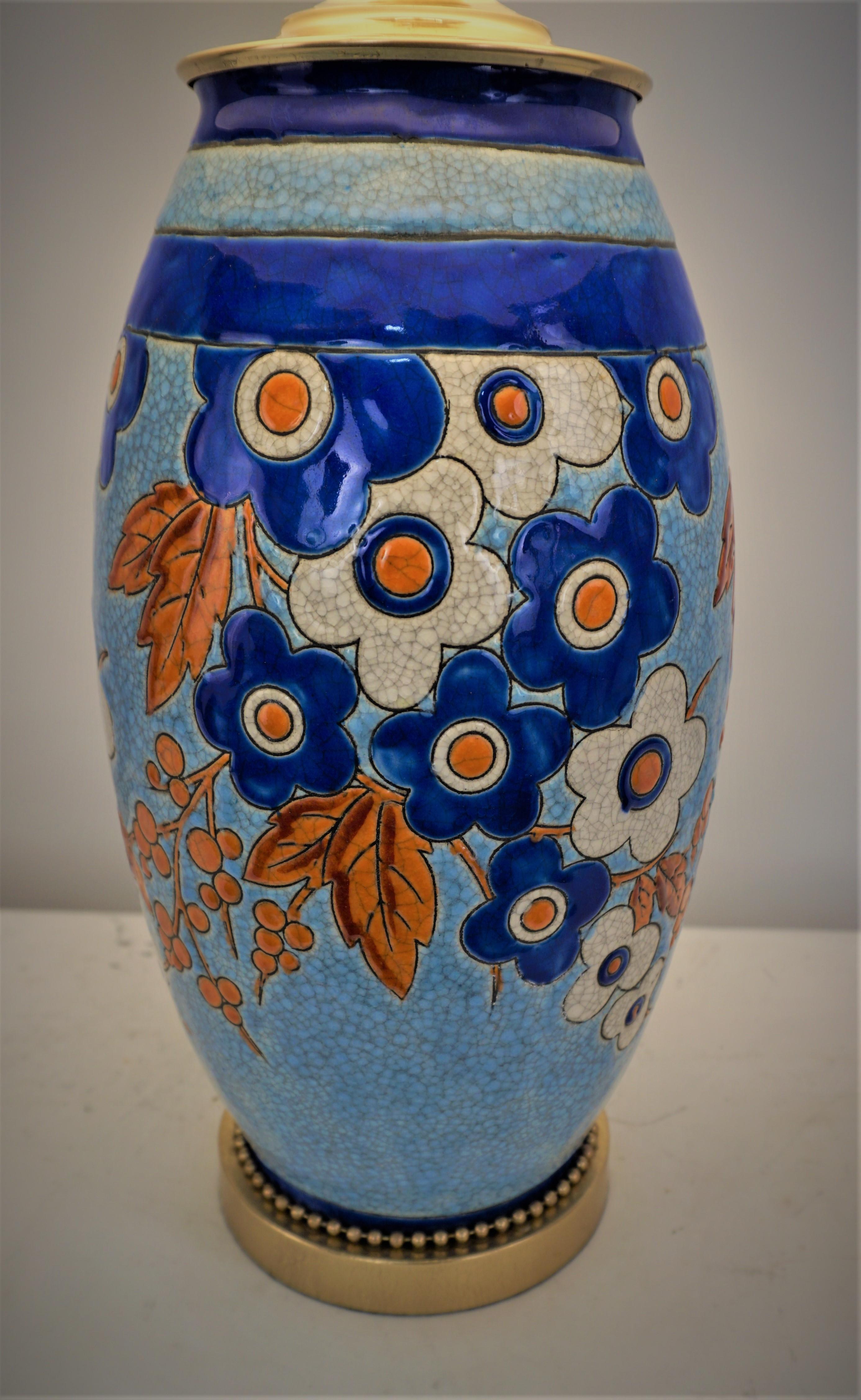 Un magnifique vase coloré en céramique de Boch, conçu par Charles Catteau, a été transformé en une élégante lampe de table avec une base et des ferrures en bronze et un abat-jour en soie rigide. 