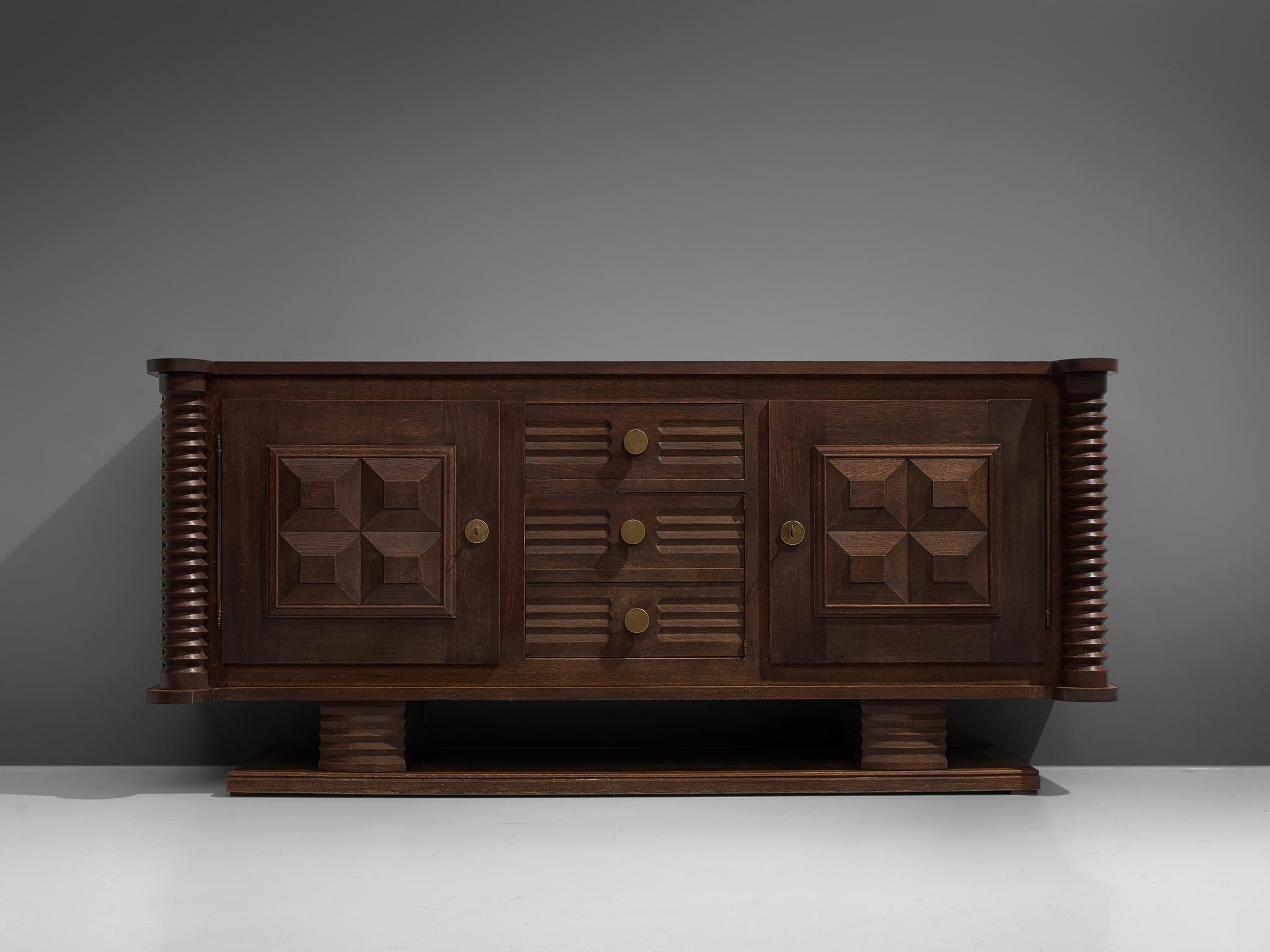 Charles Dudouyt, credenza, wood, circa 1925.

This sturdy credenza in oak with cylinder wood work is a truly sculptural piece. This two-door and three-drawers sideboard is equipped with several shelves and drawers which provide plenty of storage