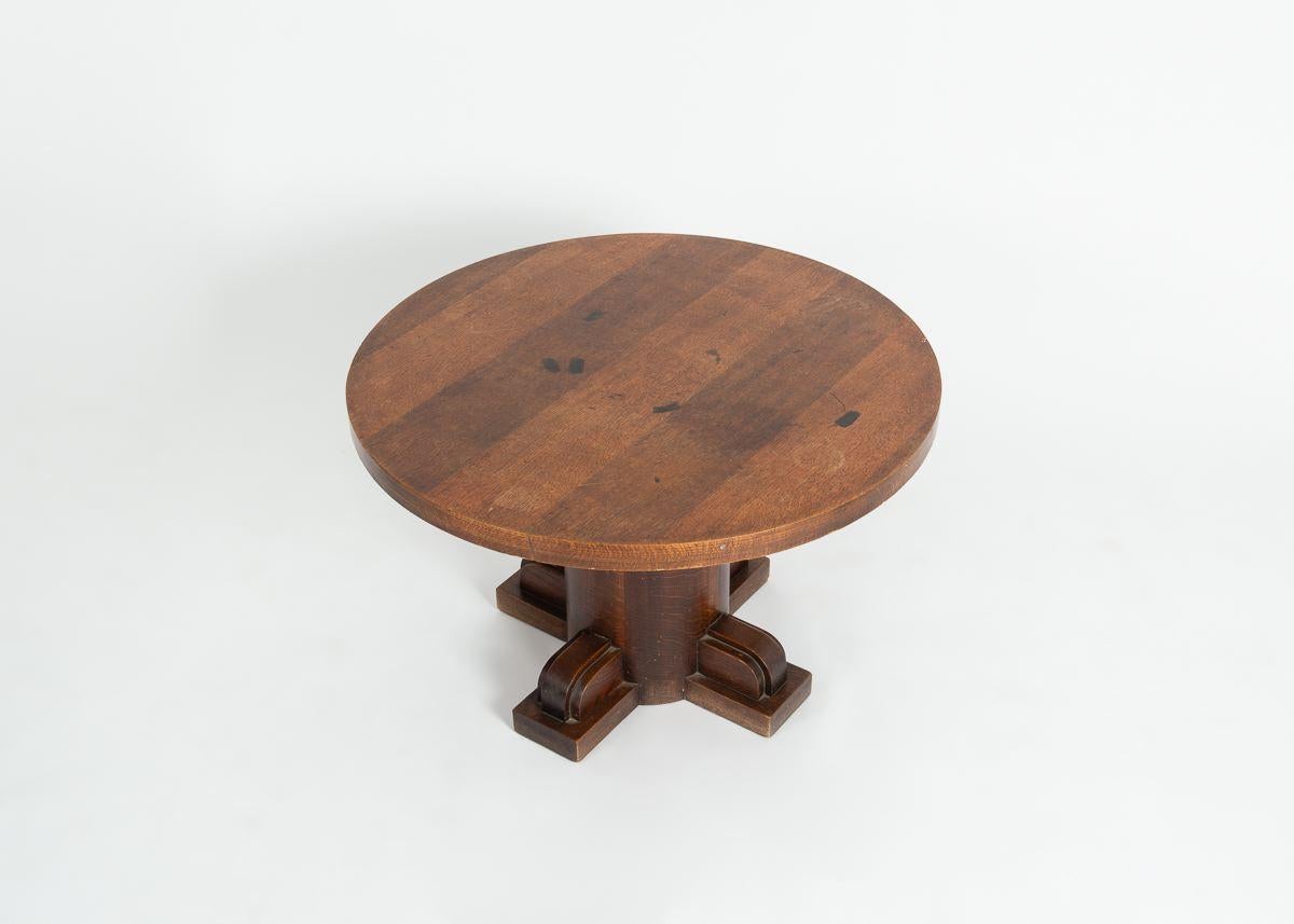 A quadrupedal pedestal coffee table in oak by Charles Dudouyt possesses a round, and a thick columnar support.