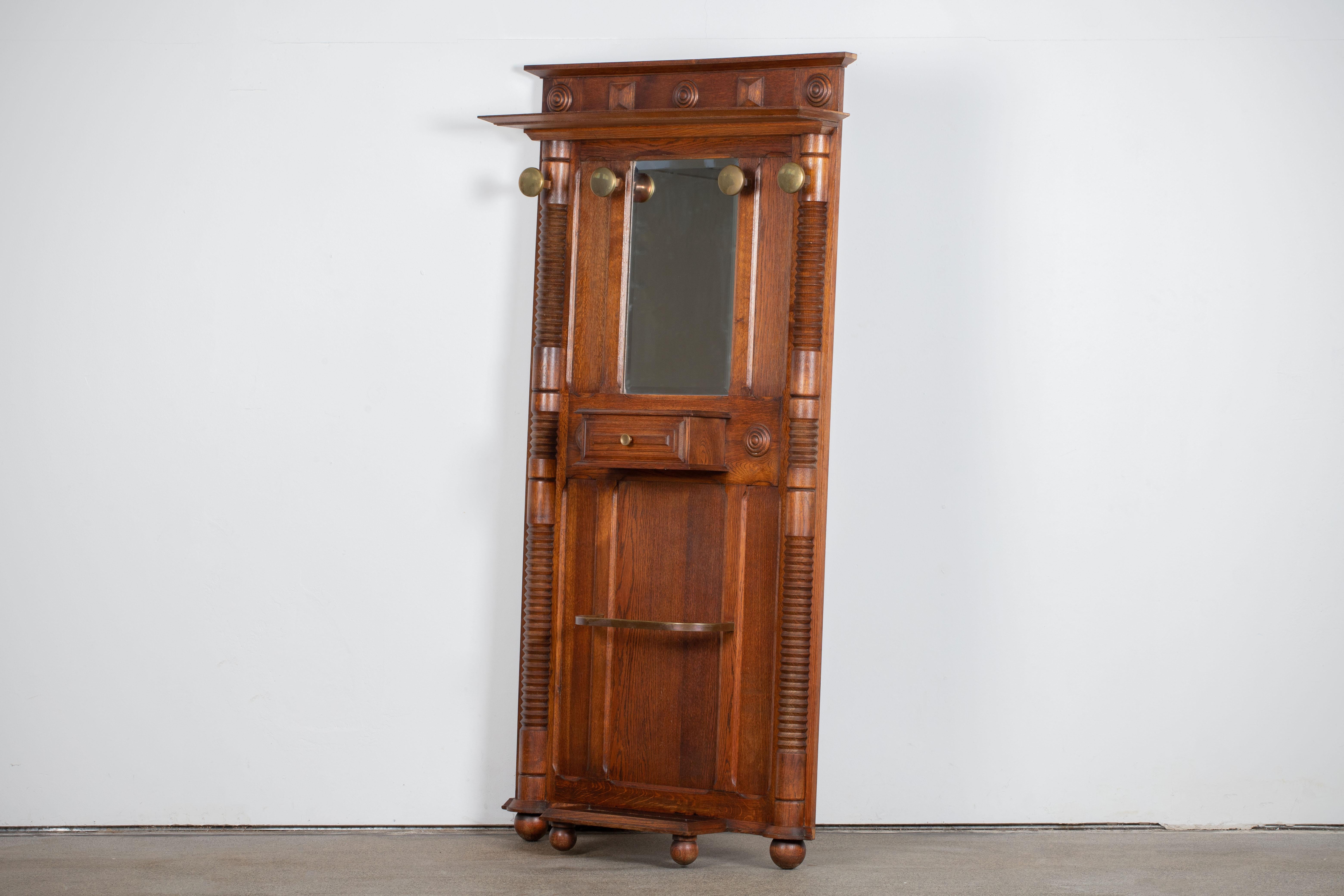 Brutalist oak hall hat and coat stand by Charles Dudouyt, 1940.
Features a shaped top cornice with handcarved details, four brass coats hooks, a central mirror, a tablet with a single drawer and an umbrella stand.

This truly unique piece