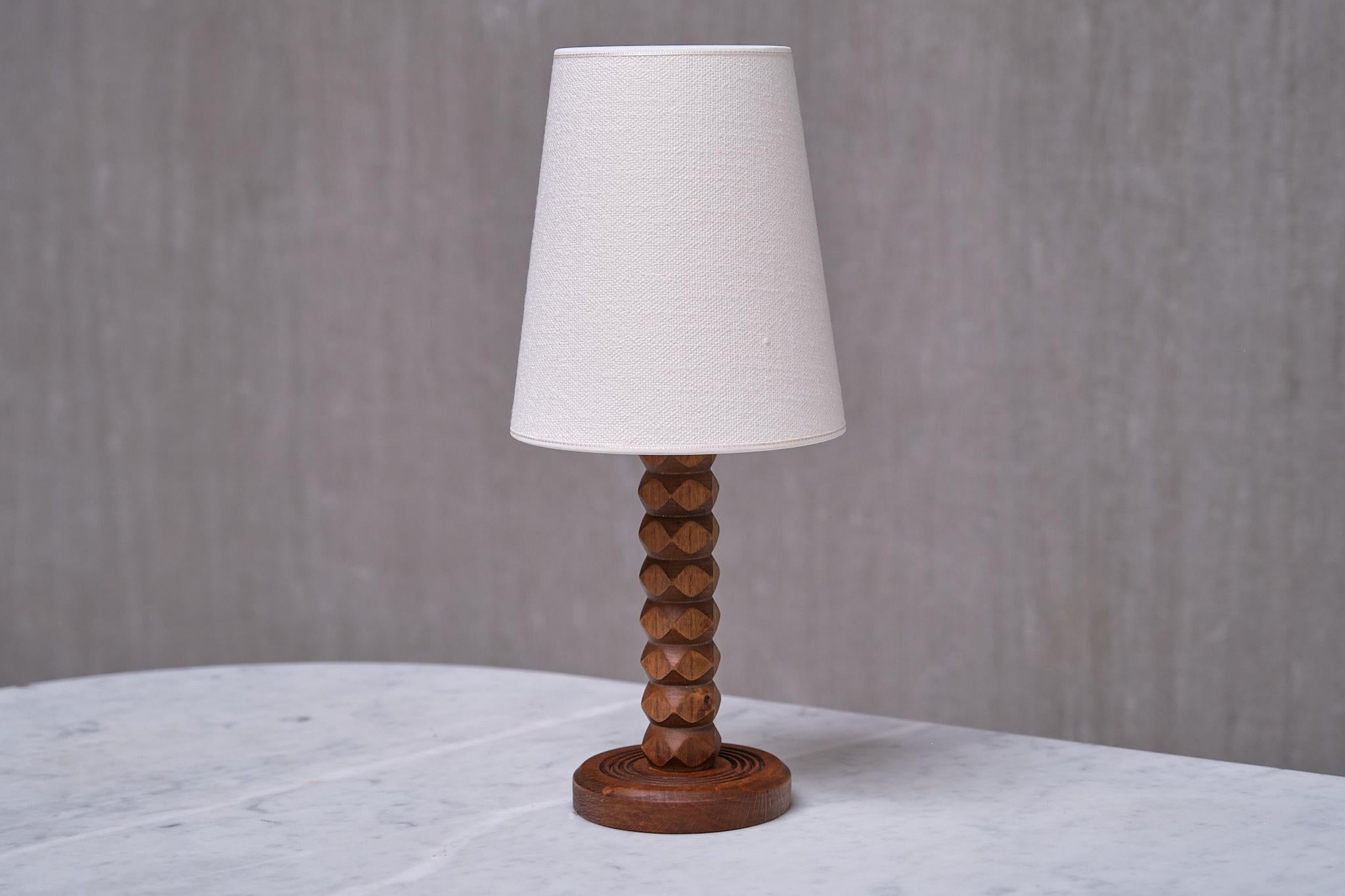 This rare table lamp was produced in France in the 1950s. The rustic and elegant design is attributed to Charles Dudouyt. The different carved shapes of the wood illustrate the craftsmanship and originality of Dudouyt's production.

The lamp is made