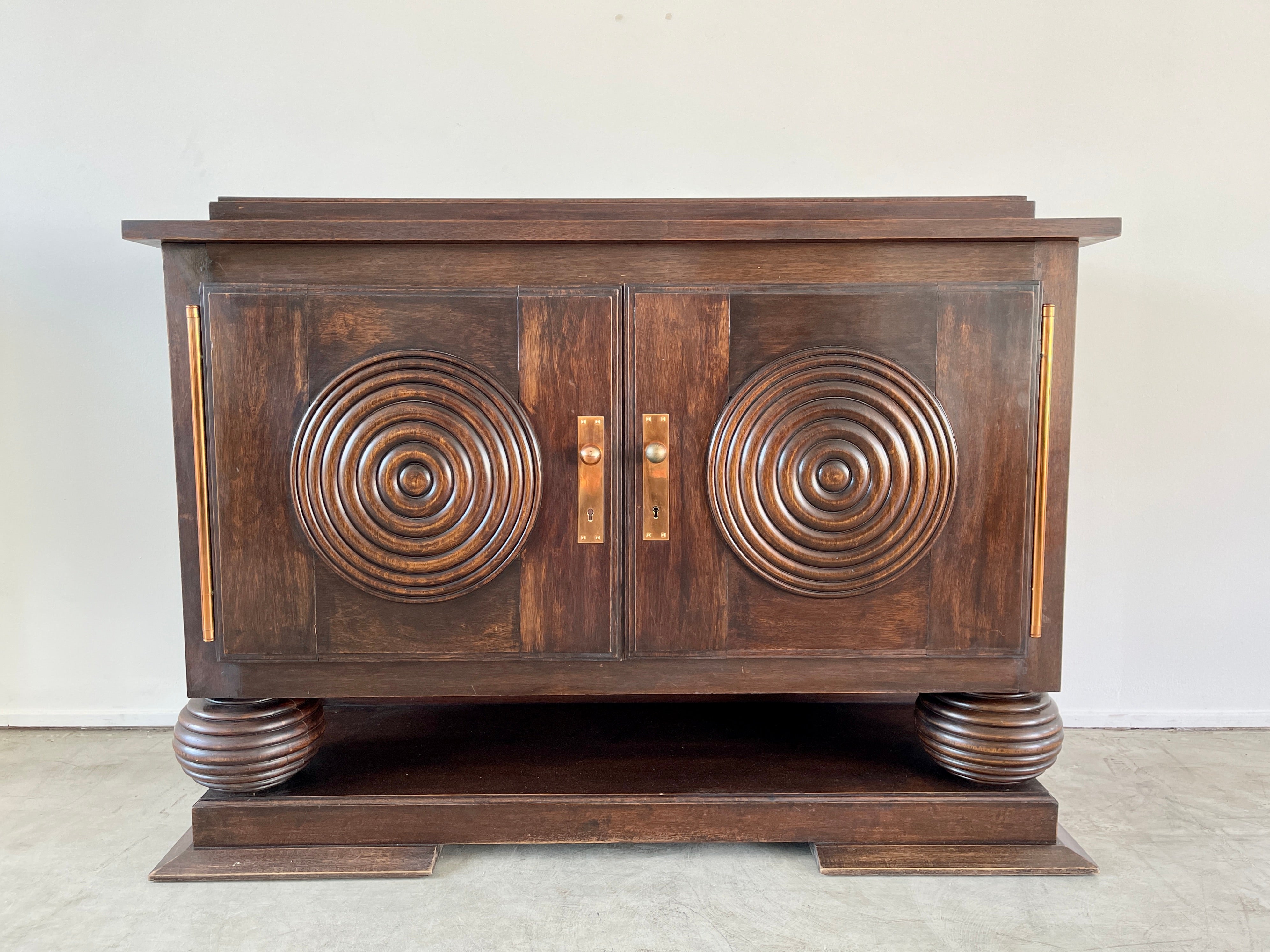Charles Dudouyt cabinet floating on giant carved ball feet.
Wonderful original rich patina
Cabinet have 2 doors with carved concentric circles which opens to shelving 
Copper / brass hardware.